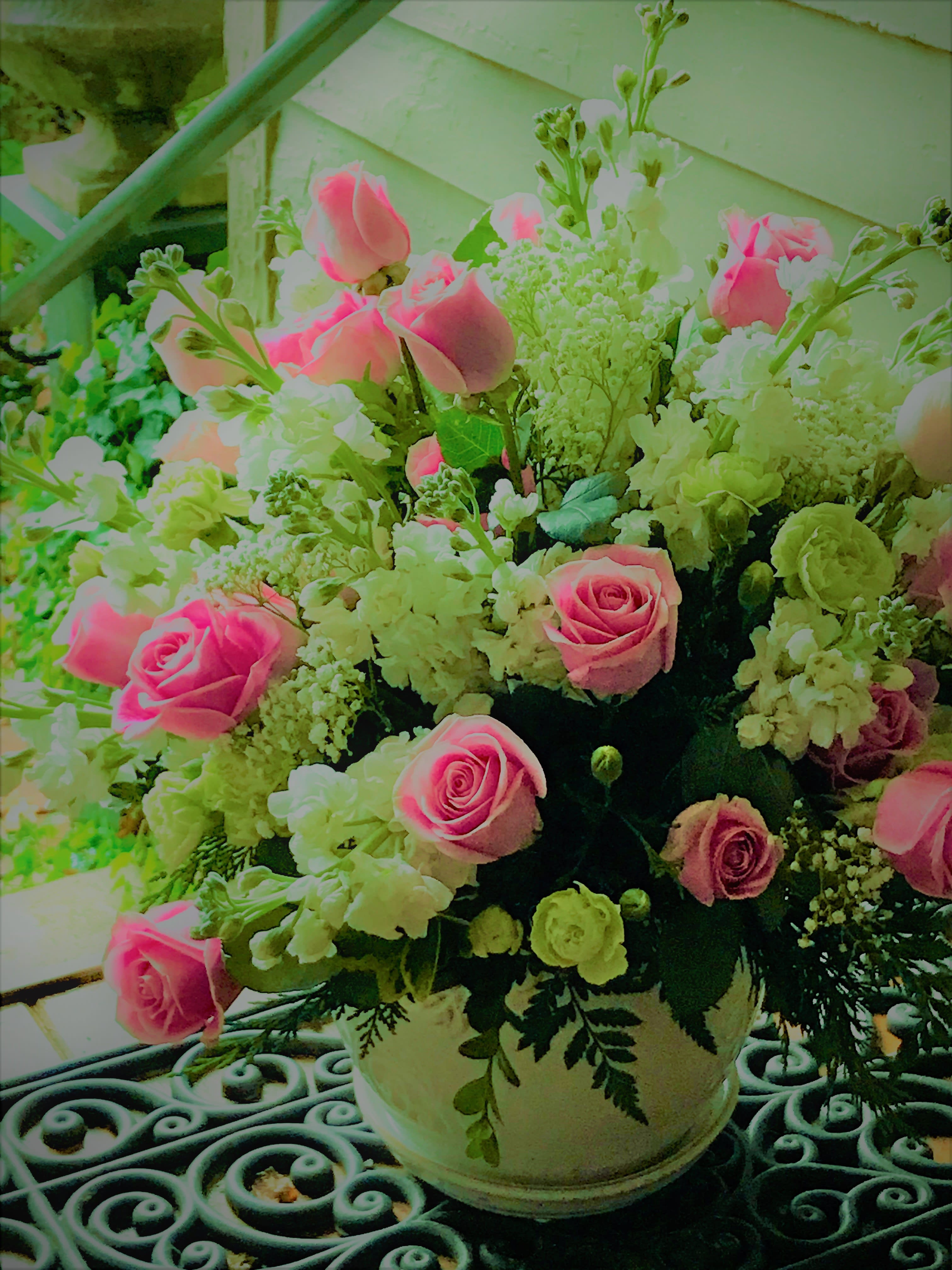 Pink roses and white flowers arranged in a white vase