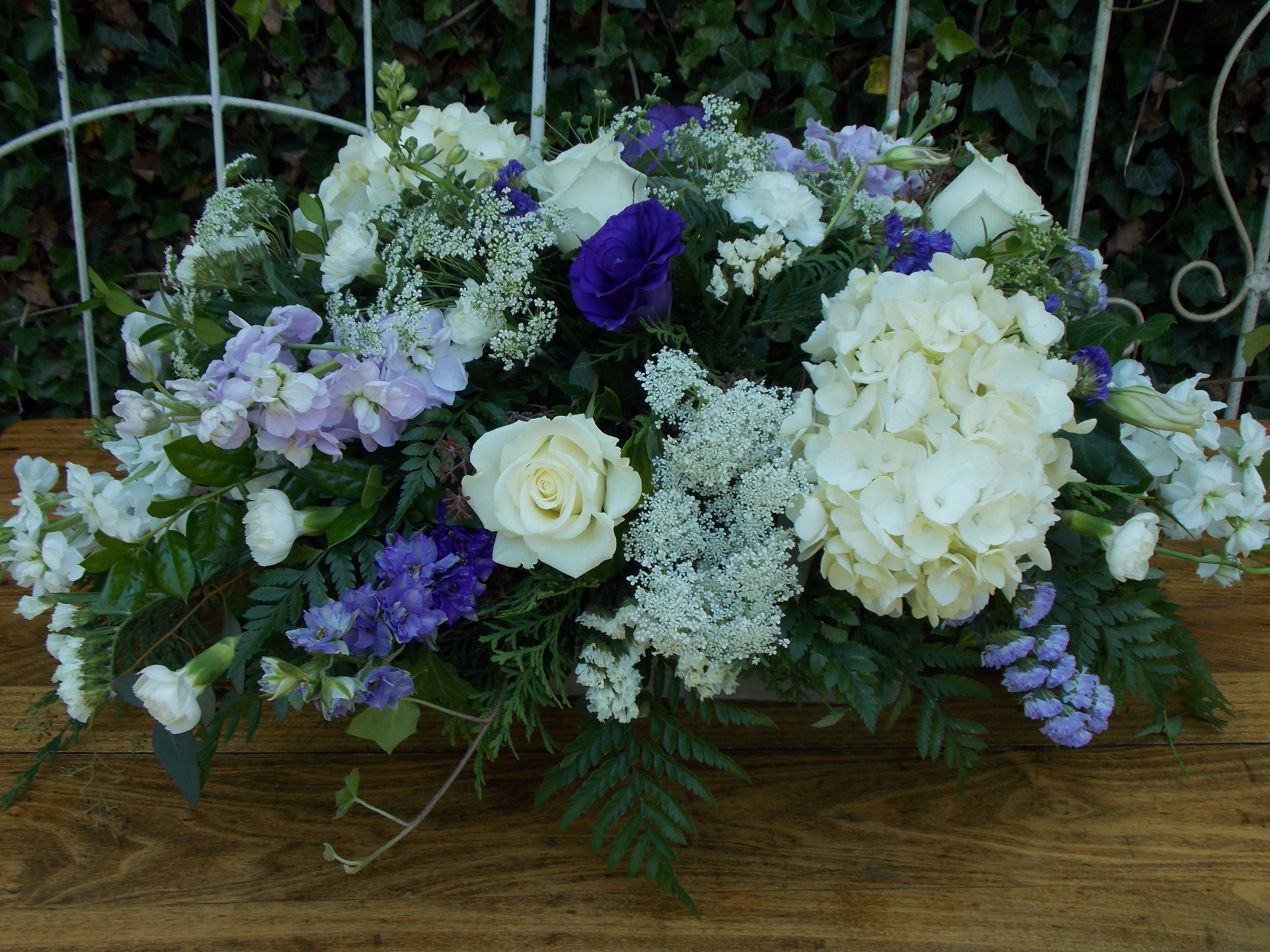 Low floral arrangement with white roses, hydrangeas, and purple blooms