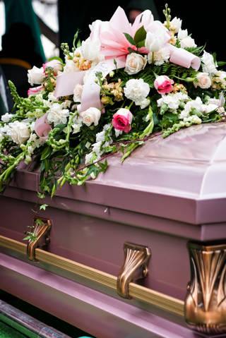 Pink and white floral casket spray on a mauve casket