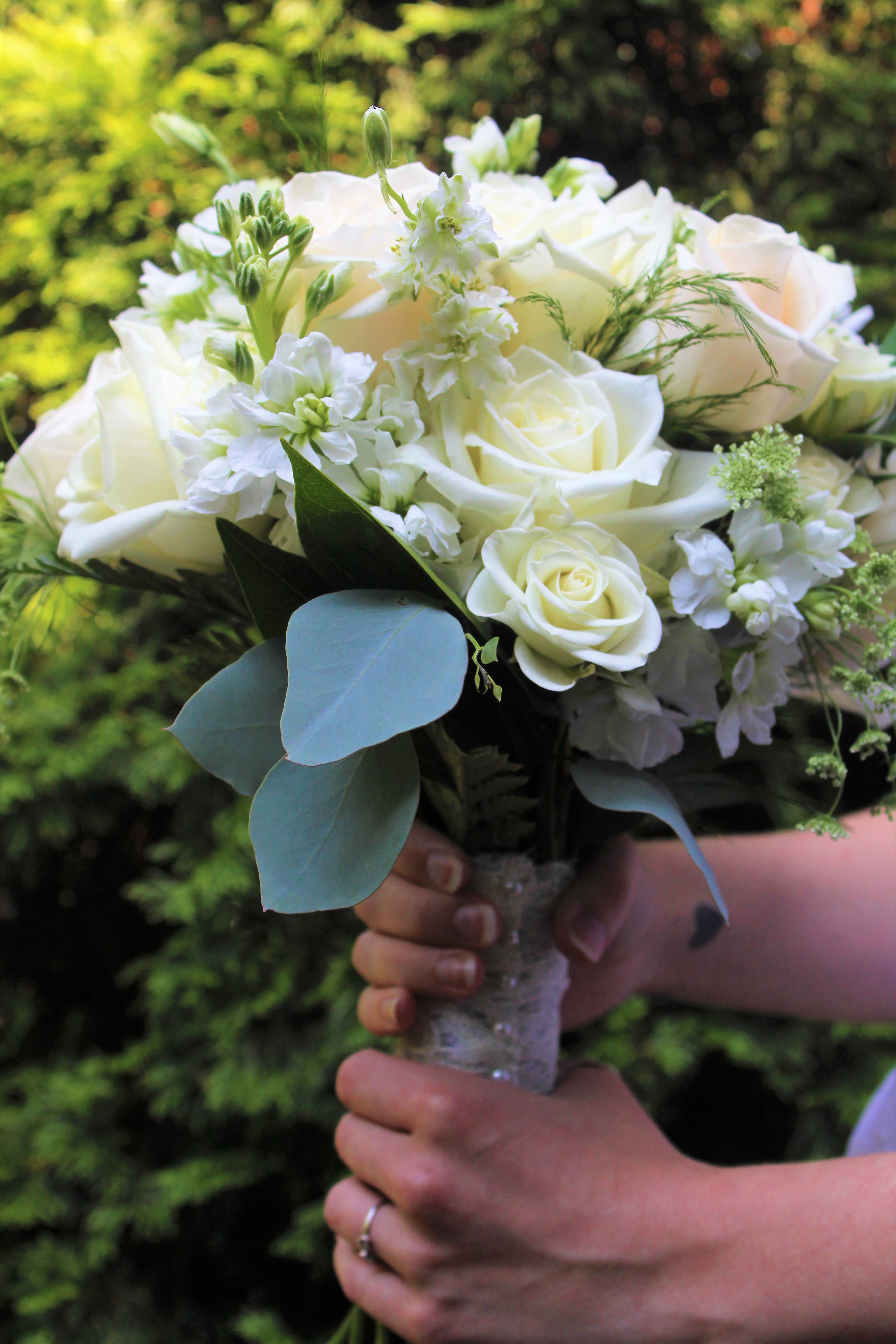 White rose bouquet with small white flowers and blue-green leaves