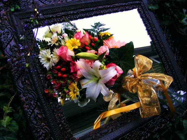 Mixed bouquet with lilies, roses, and daisies tied with a gold ribbon