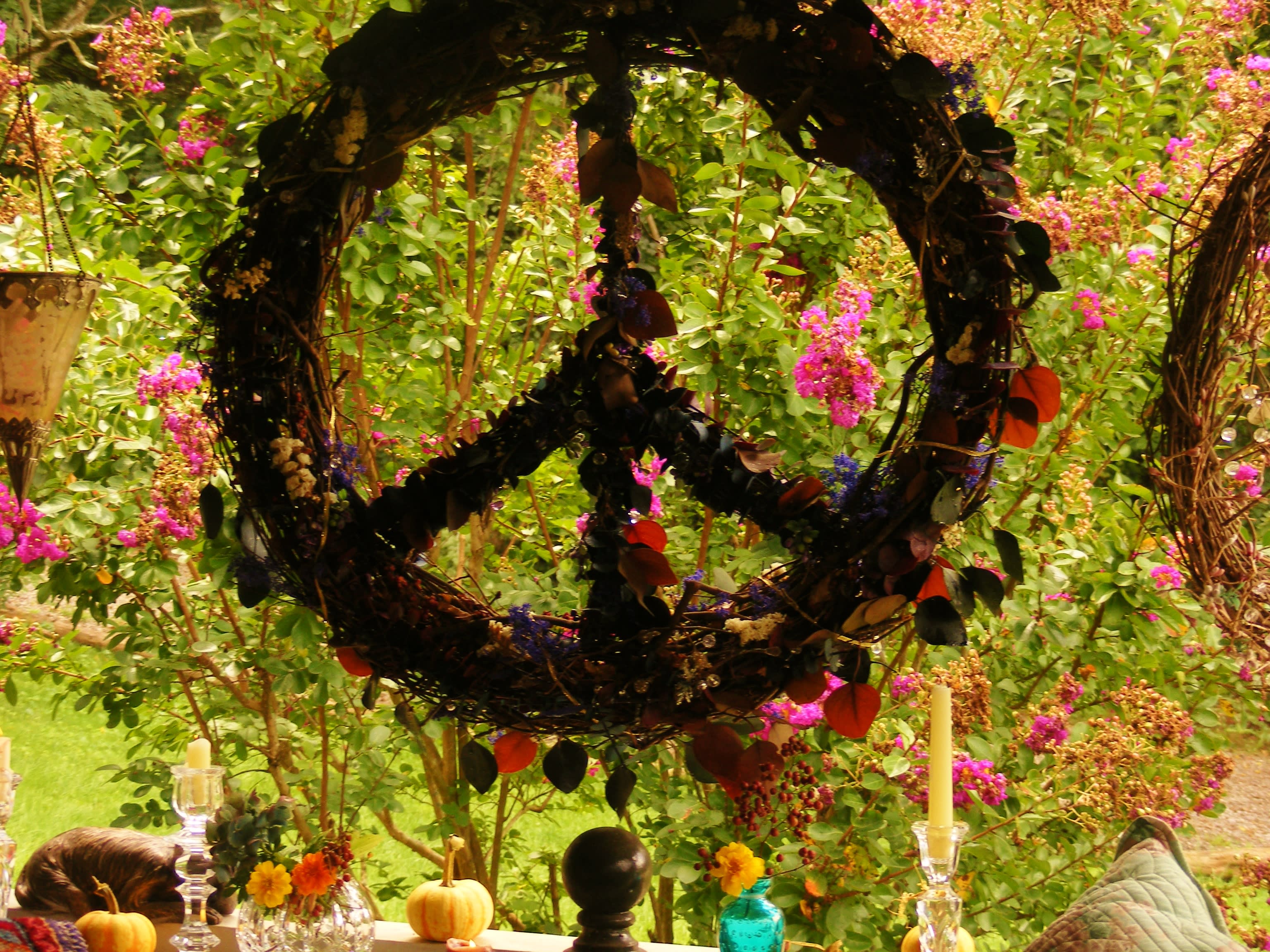 Large wreath with dark leaves hanging over a table in a garden setting