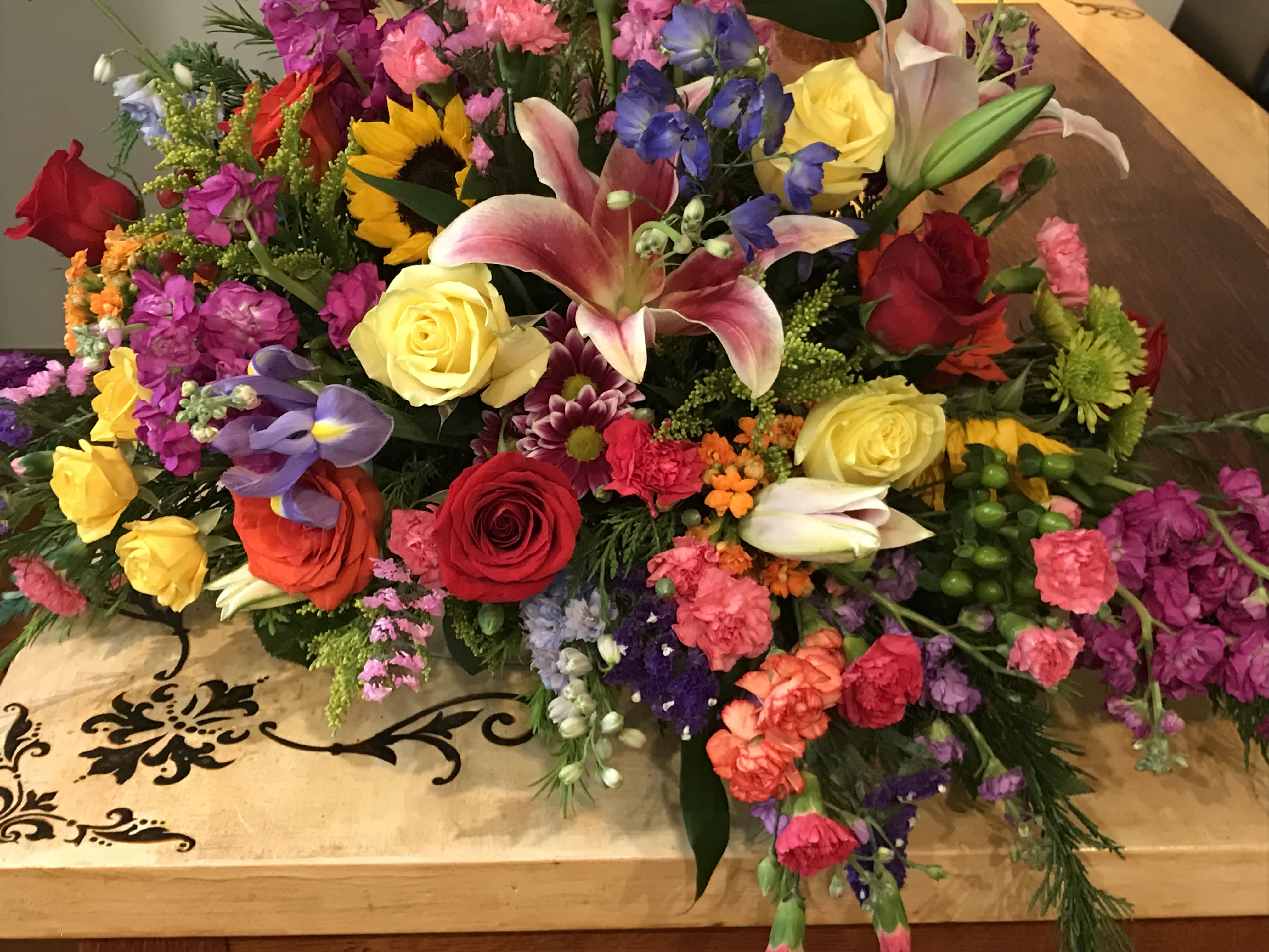 Colorful mixed flower arrangement with roses, lilies, and sunflowers on a table
