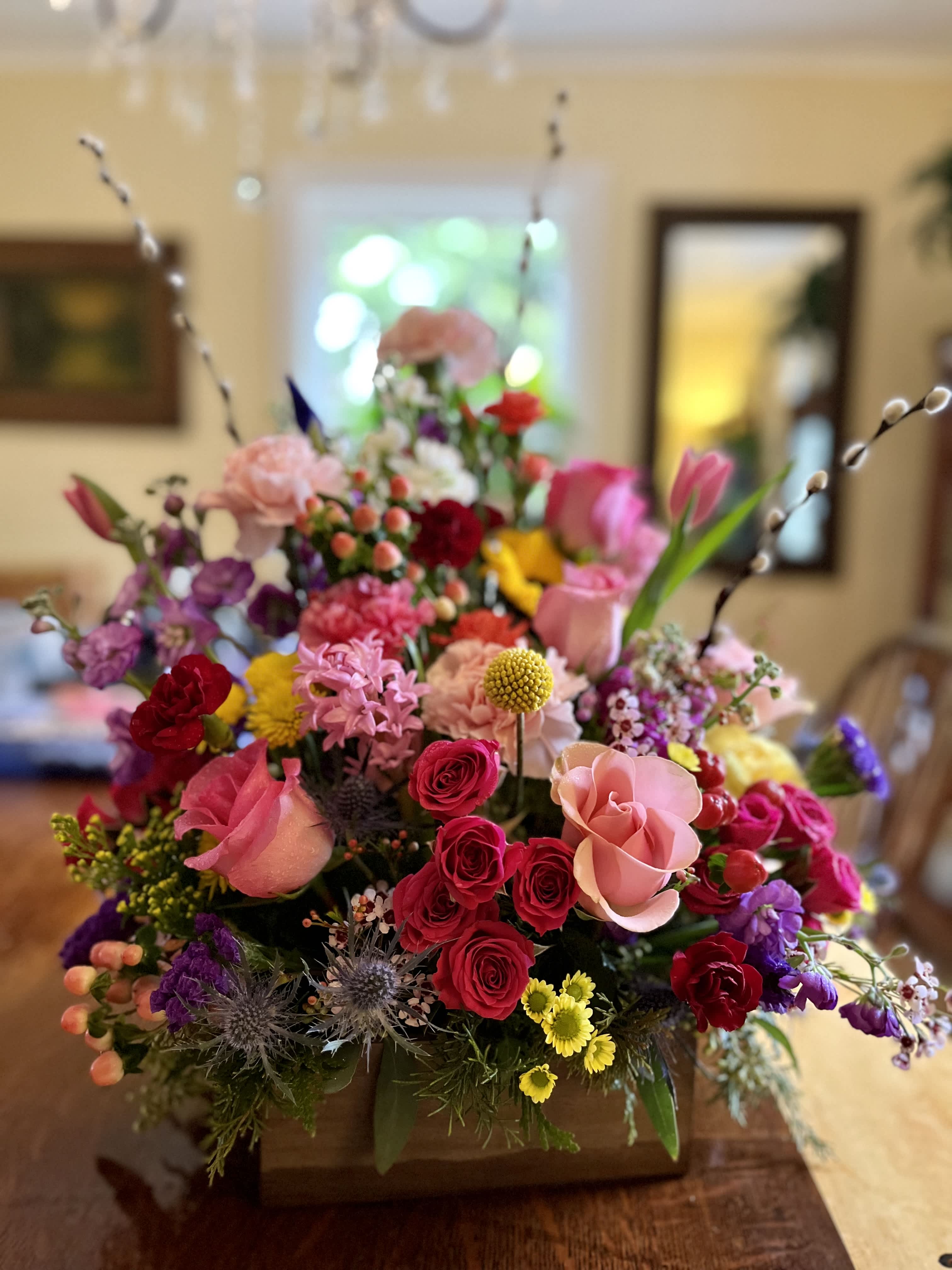 Colorful mixed flower arrangement in a wooden box with tall pussy willow stems