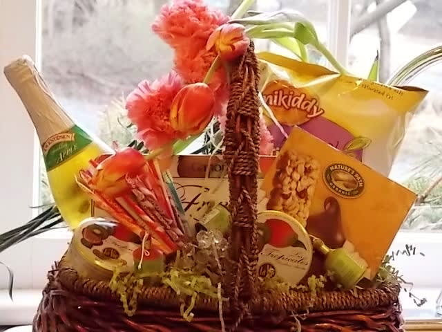 Gift basket with snacks, a bottle, and pink tulips