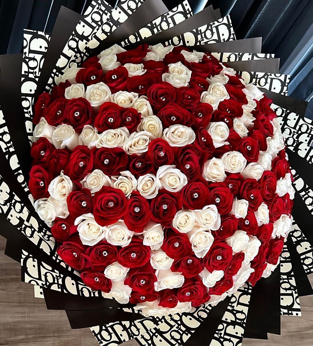 Large bouquet of red and white roses wrapped in black patterned paper