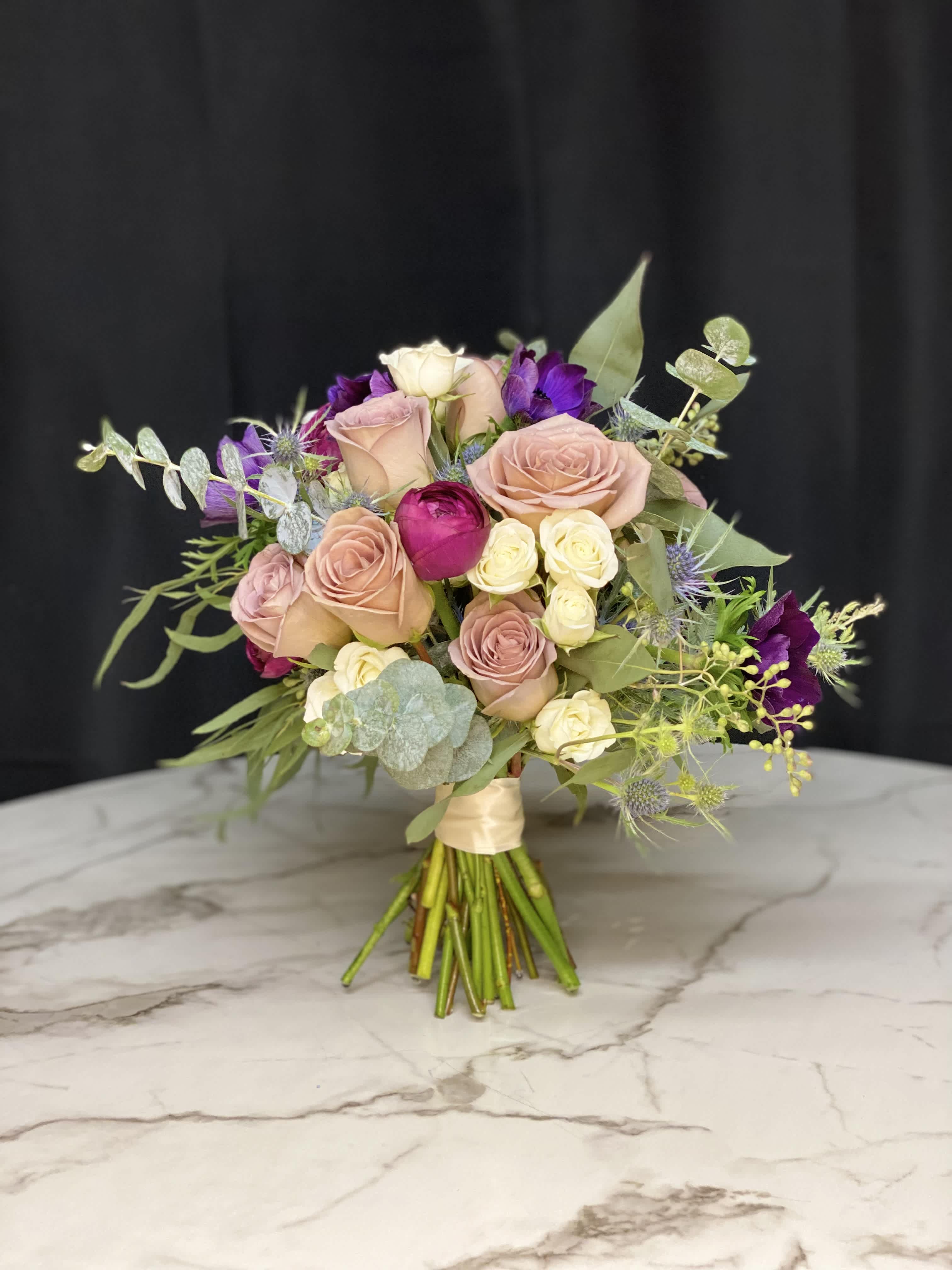 Bouquet of blush and purple roses with eucalyptus on a marble surface