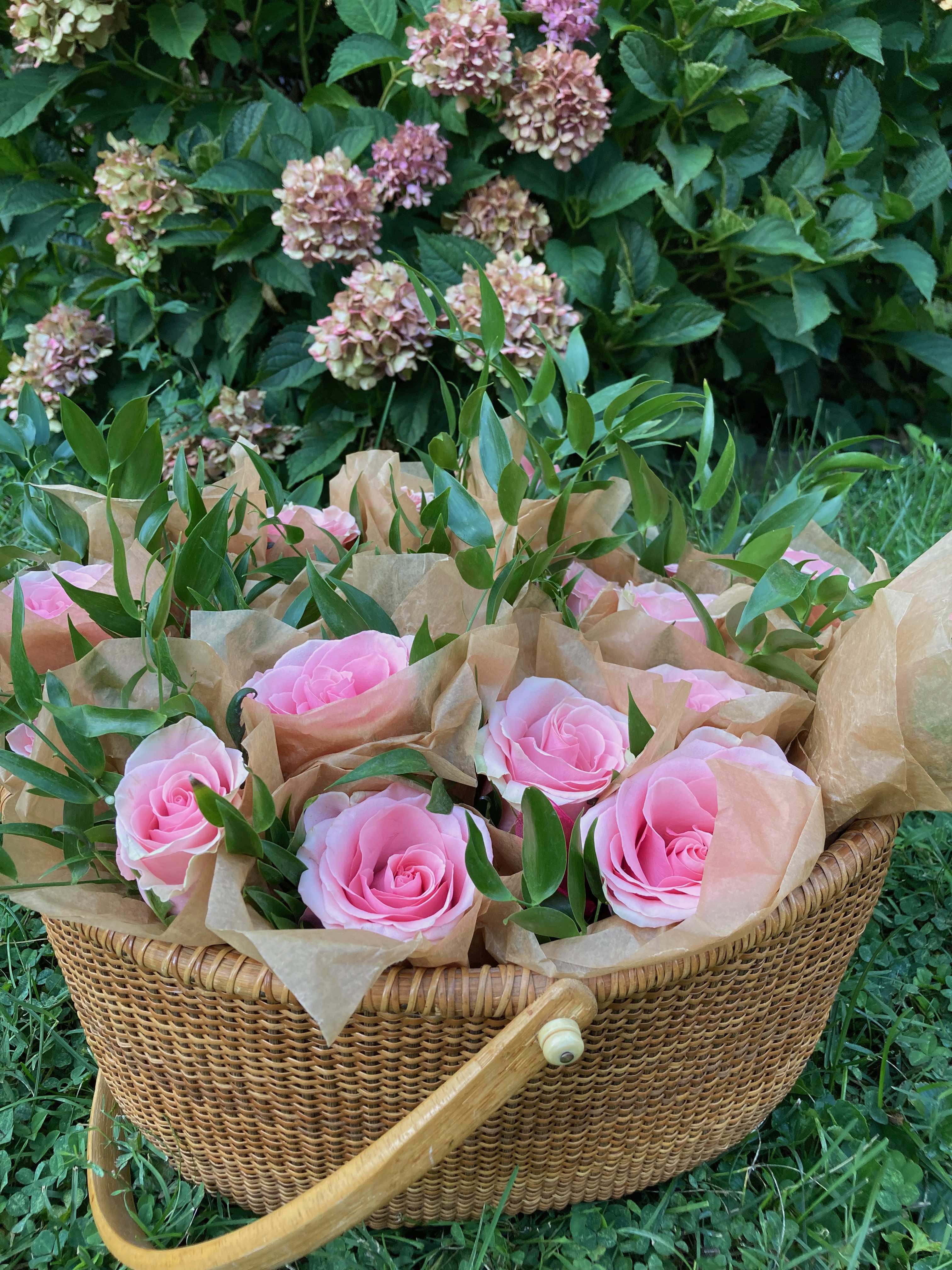 Pink roses in brown paper inside a wicker basket