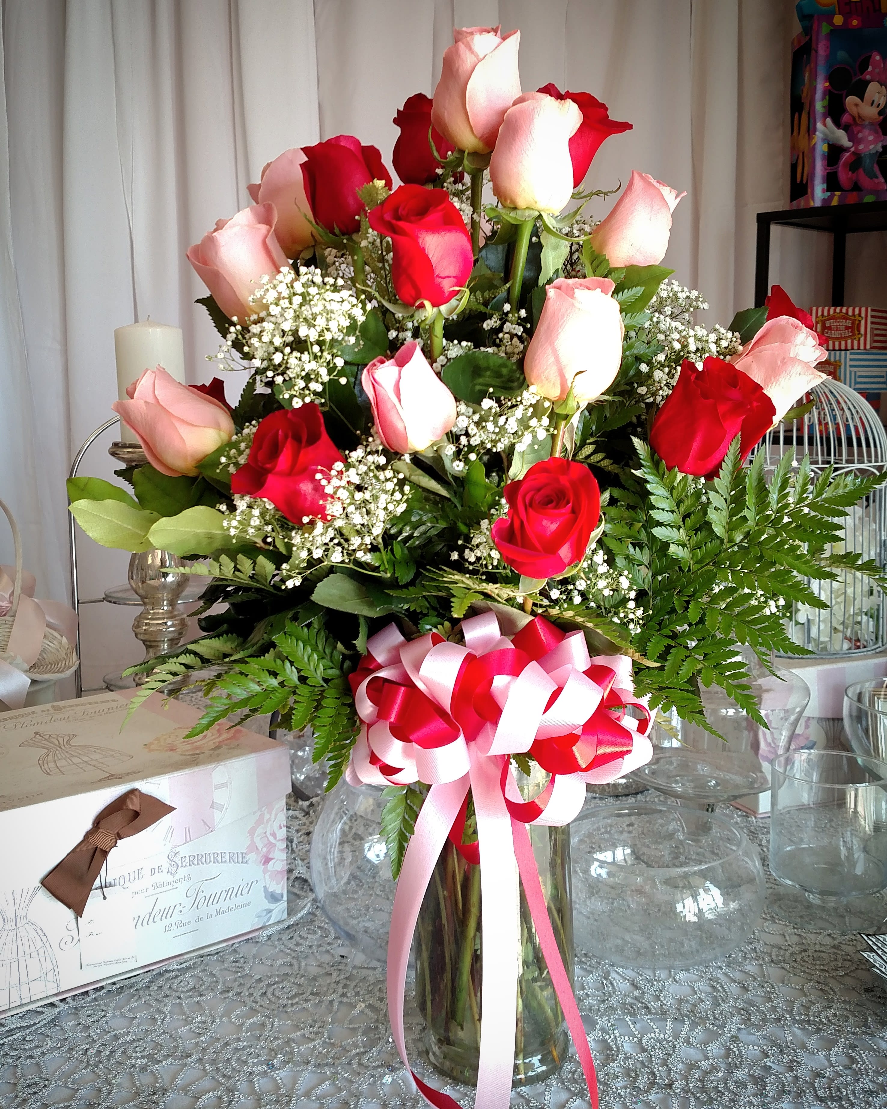 Red and pink roses in a glass vase with a ribbon bow