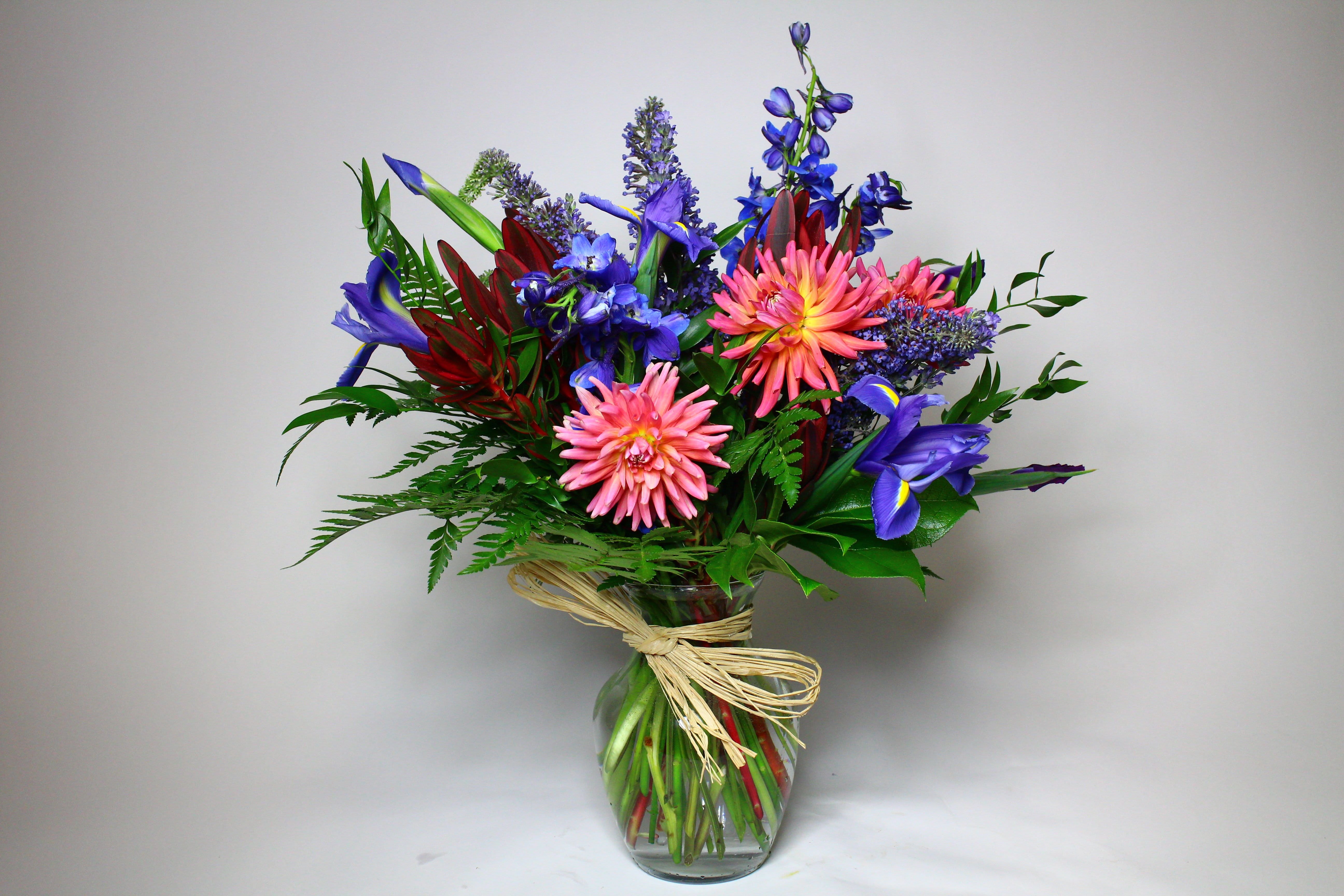 Colorful bouquet of pink, blue, and purple flowers in a glass vase