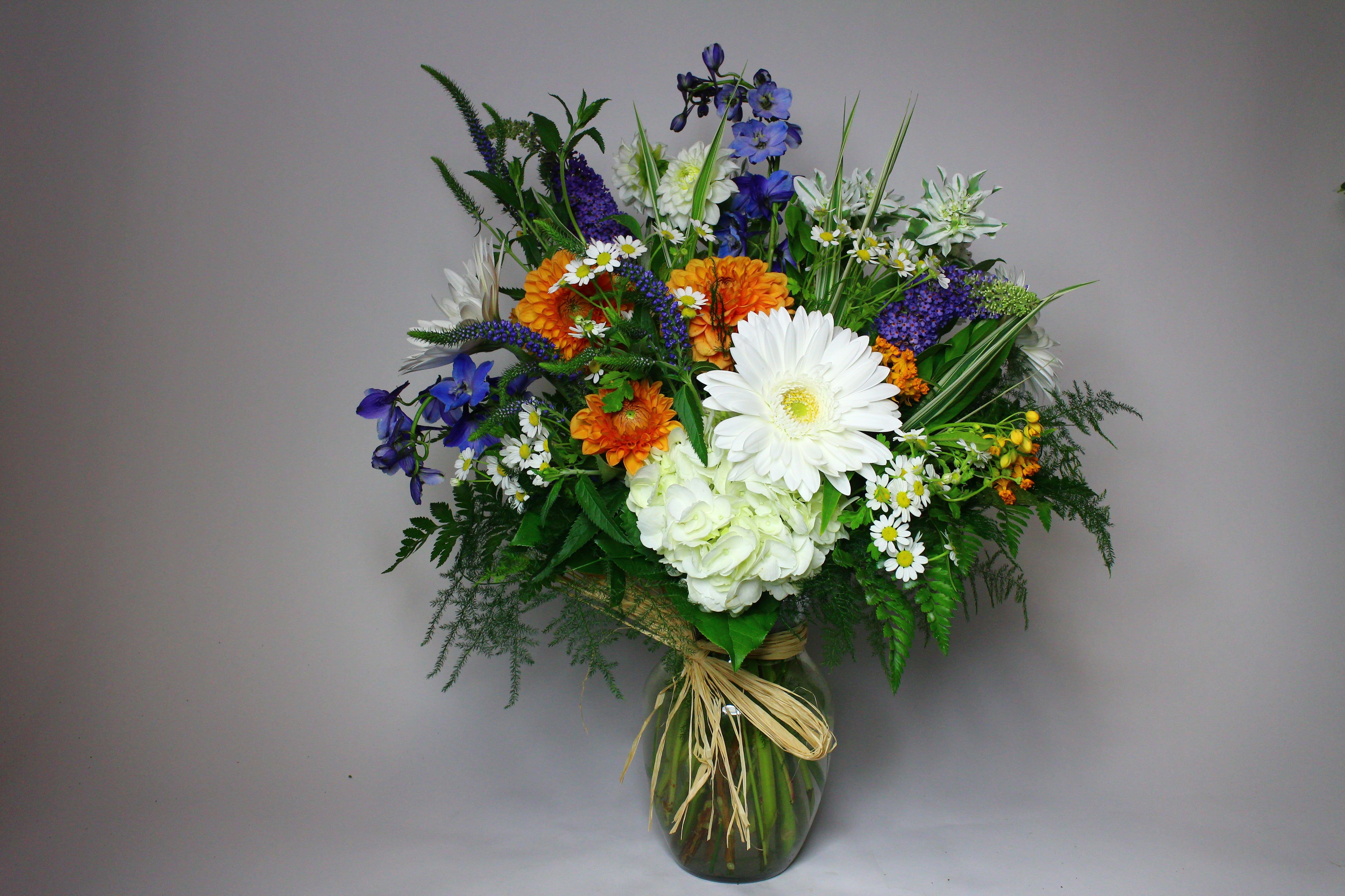Mixed bouquet in a glass vase with white, orange, and blue flowers
