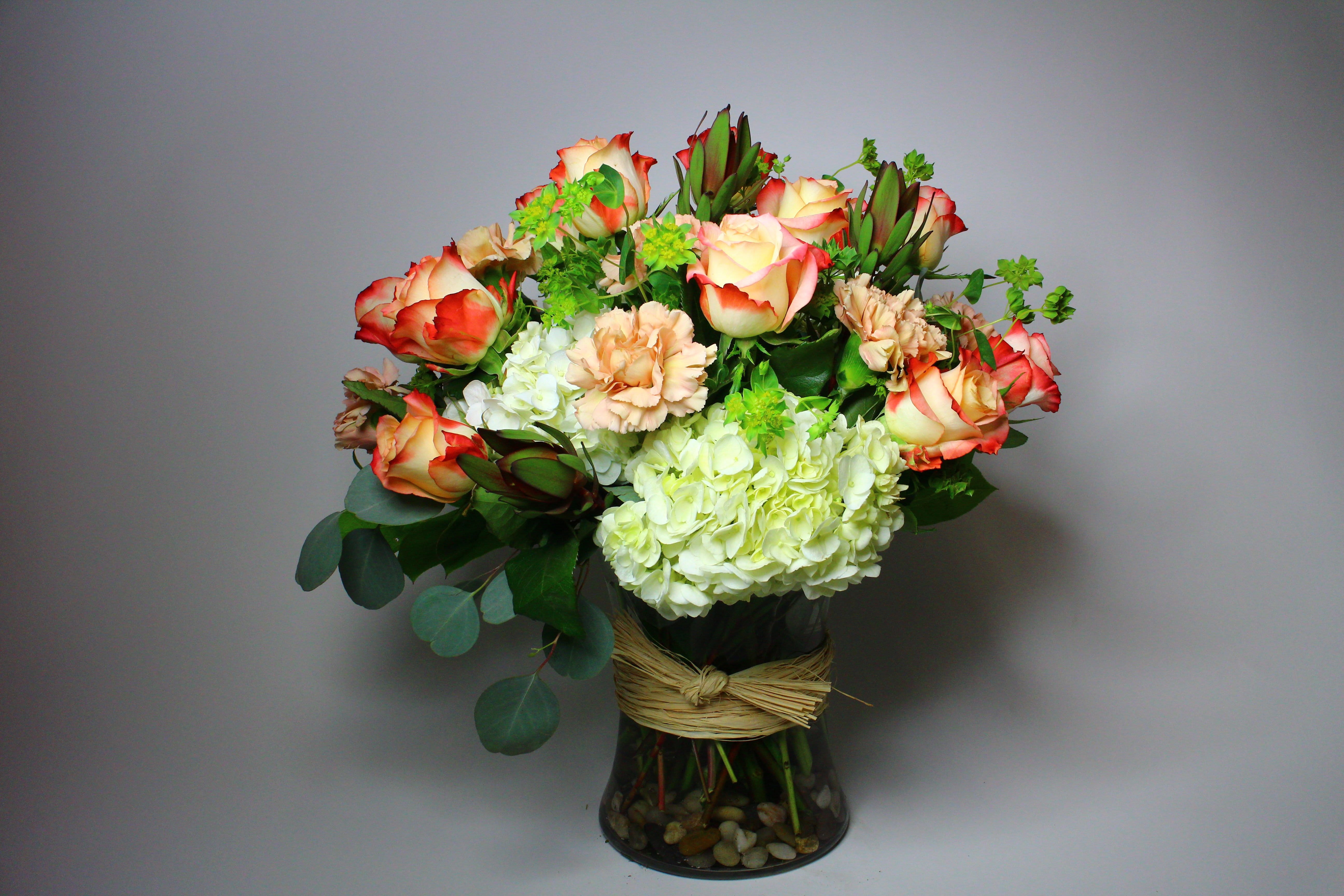 Bouquet of red-edged roses and pale hydrangeas in a glass vase