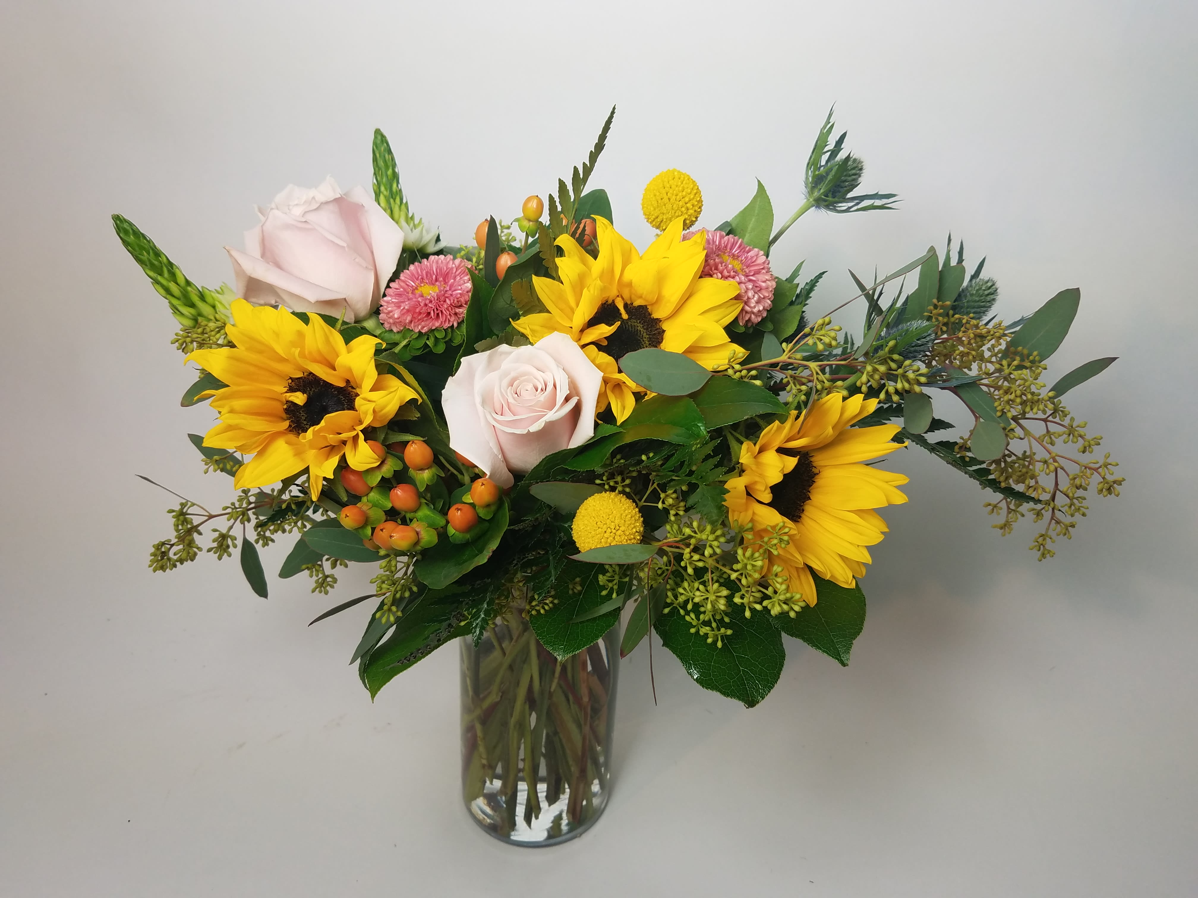 Bouquet of sunflowers and pale pink roses in a glass vase