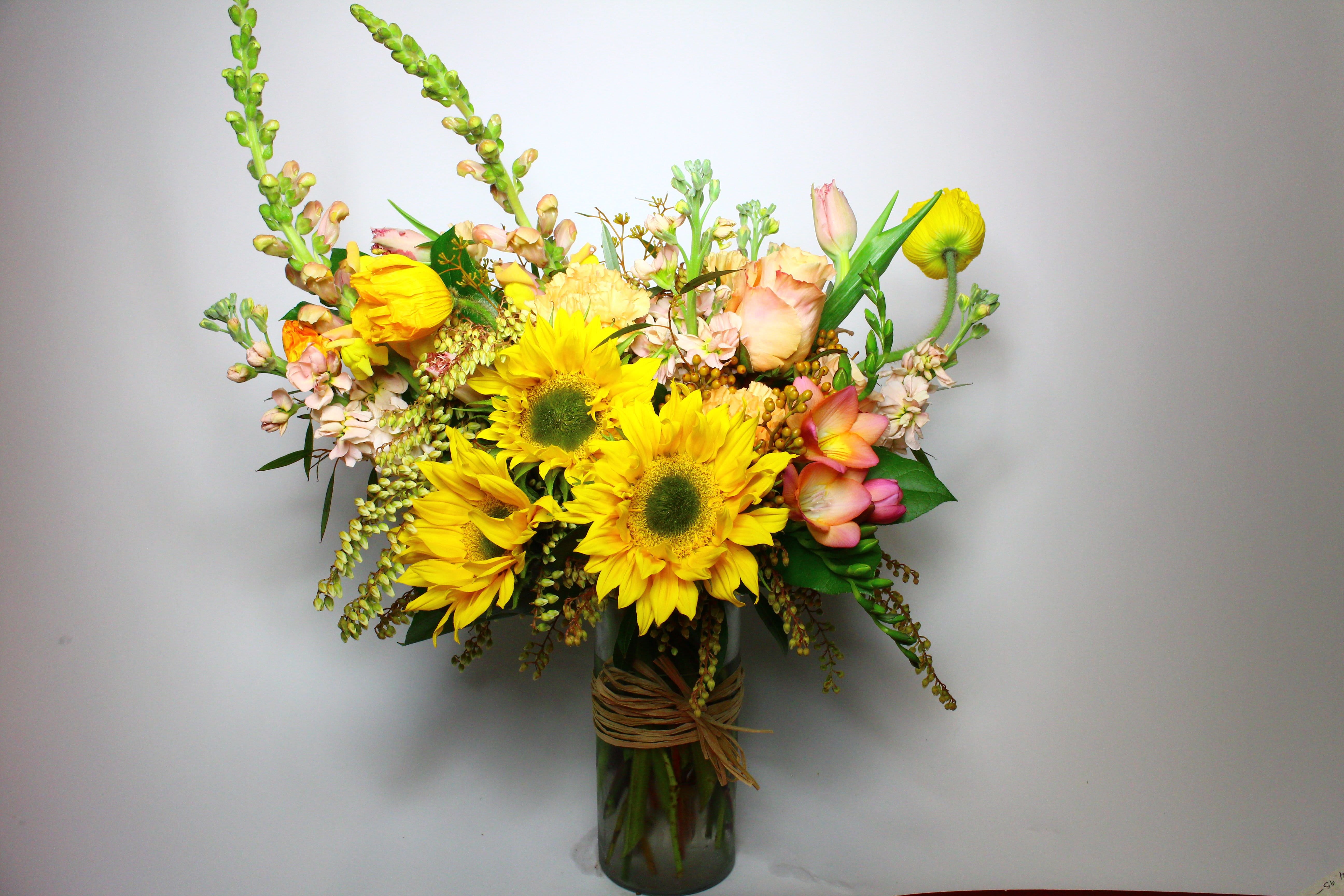 Bouquet of yellow sunflowers and pastel flowers in a glass vase