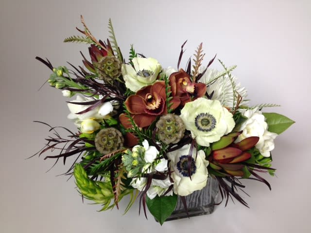 Mixed floral arrangement with white and rust blooms in a square vase