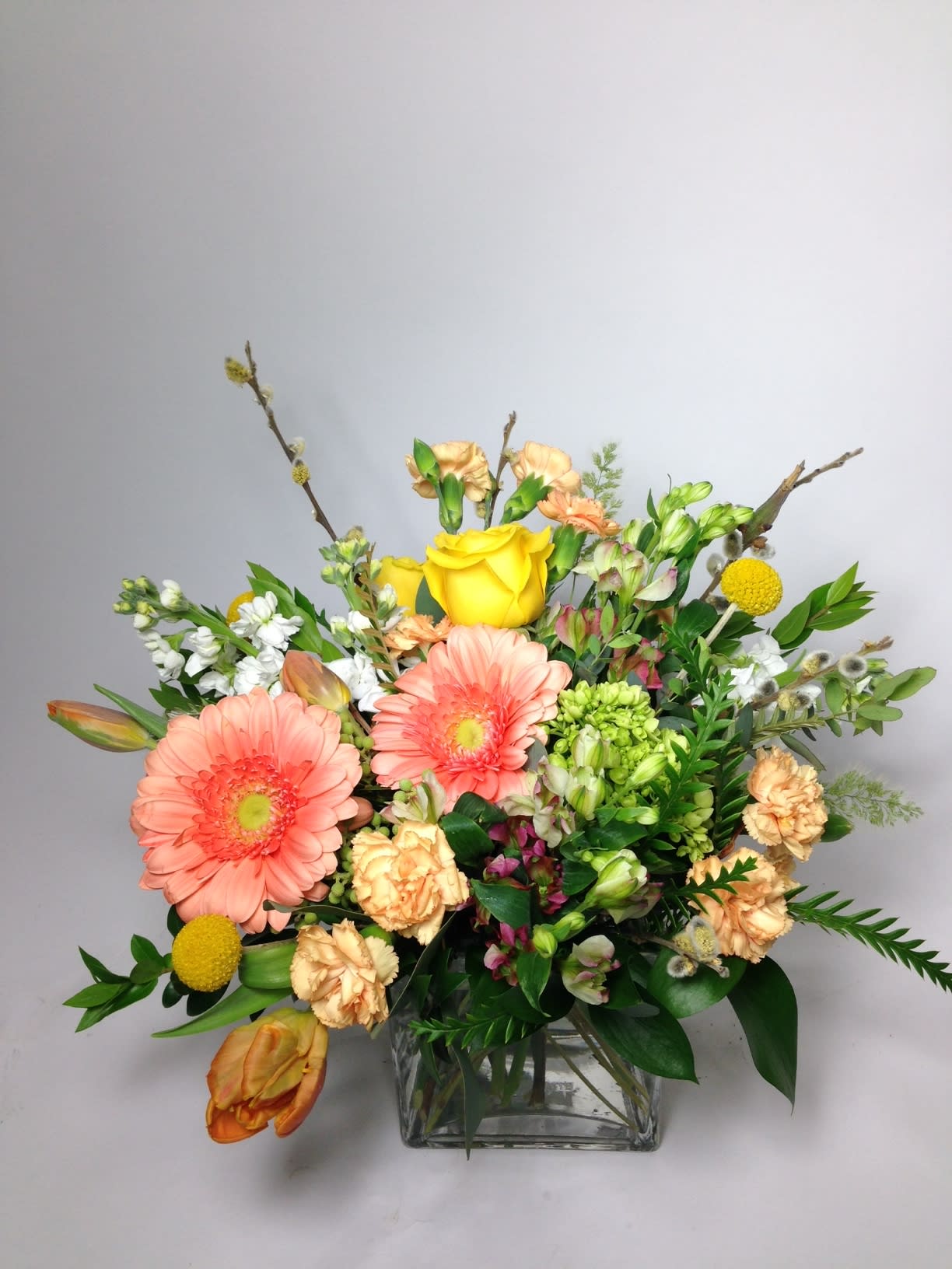 Mixed bouquet with pink gerbera daisies and yellow roses in a glass vase