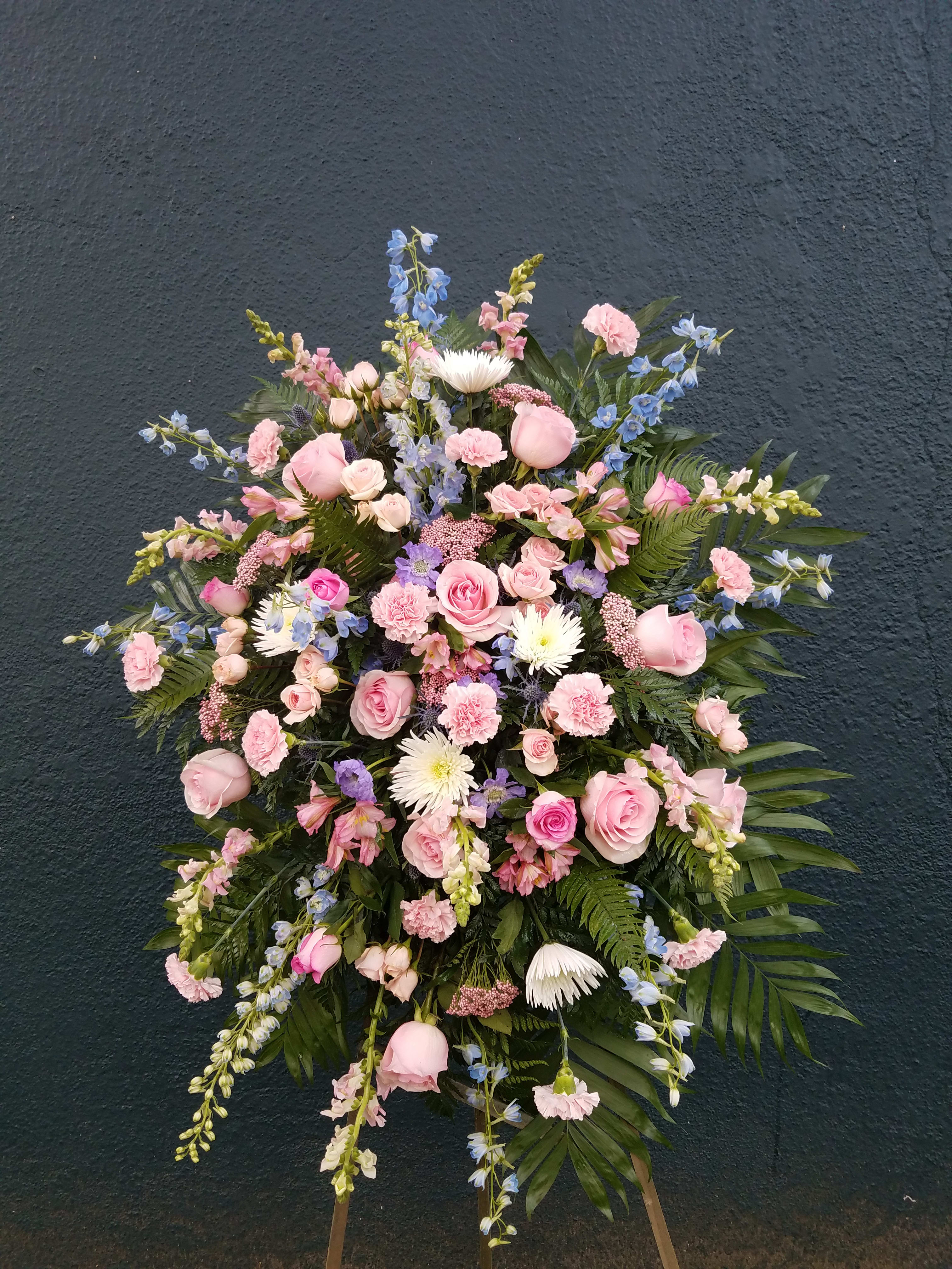 Large standing spray of pink and blue flowers on a dark wall