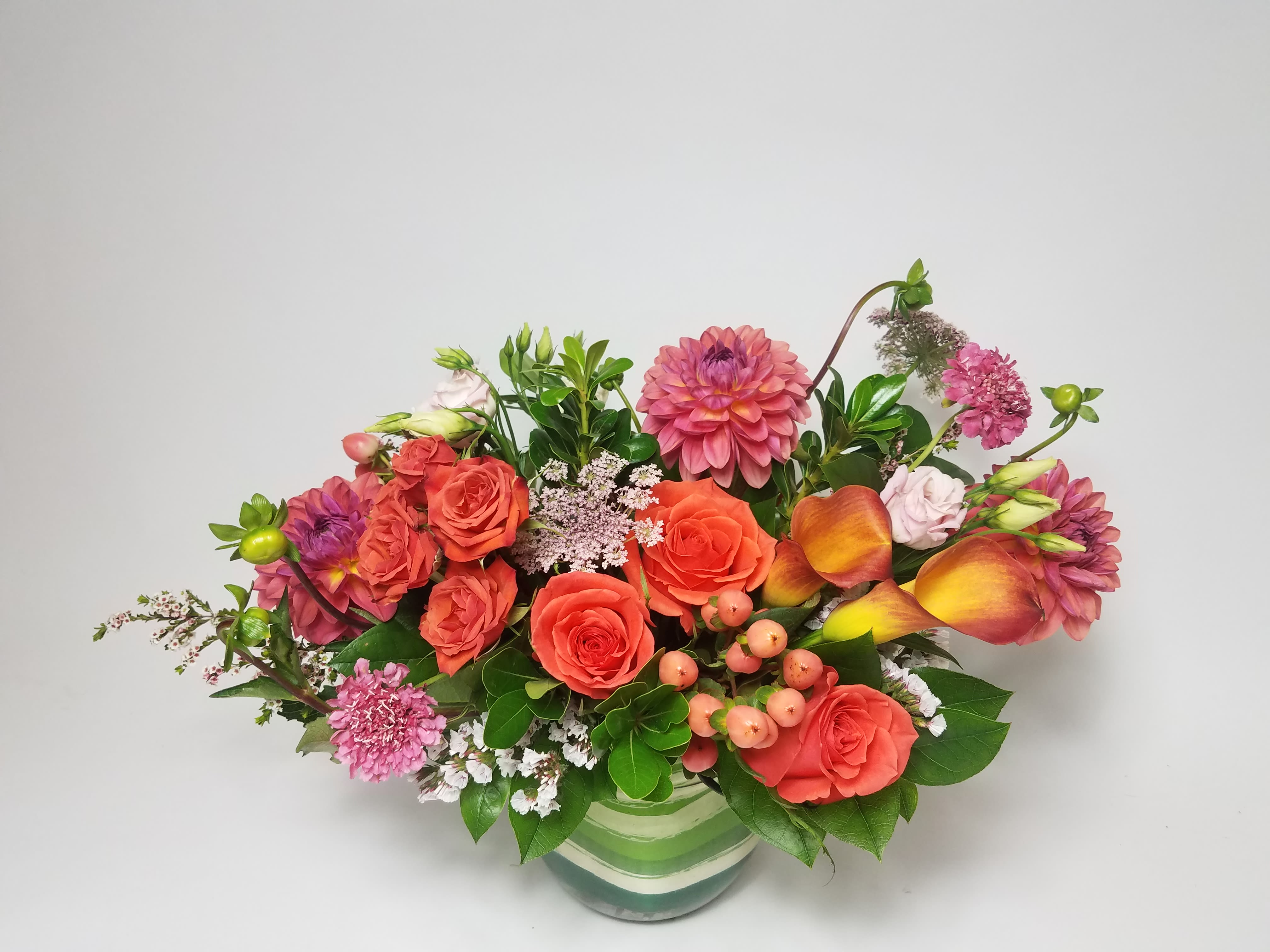 Mixed bouquet of orange and pink flowers in a striped glass vase