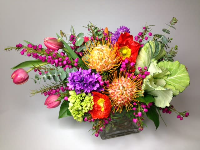 Colorful mixed bouquet in a square glass vase with pink tulips and purple blooms