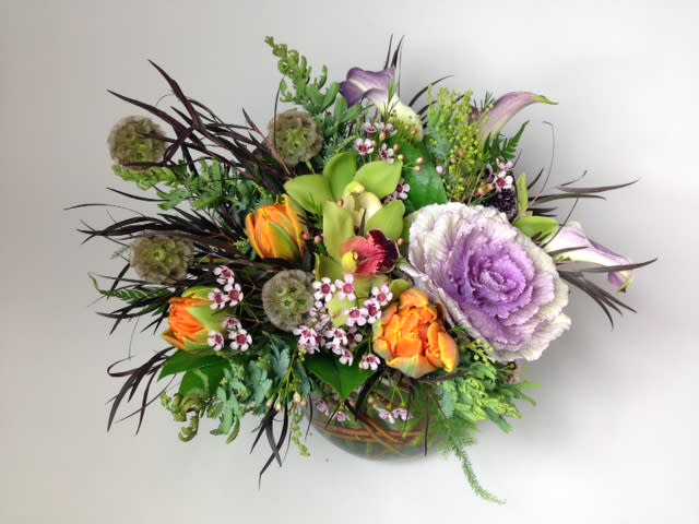 Mixed bouquet with purple cabbage roses and orange tulips in a low vase