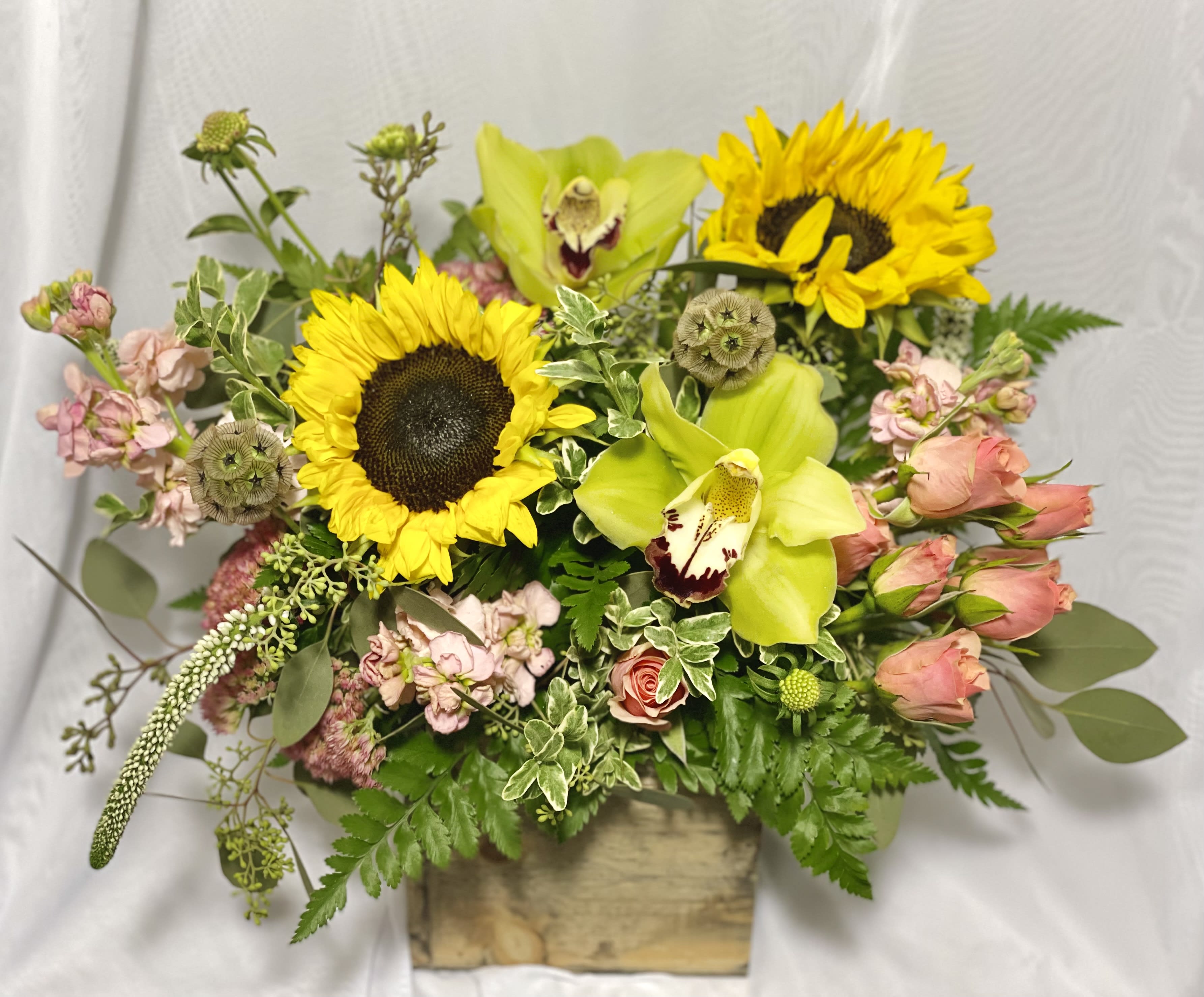 Mixed bouquet with sunflowers, green orchids, and pink roses in a wooden box