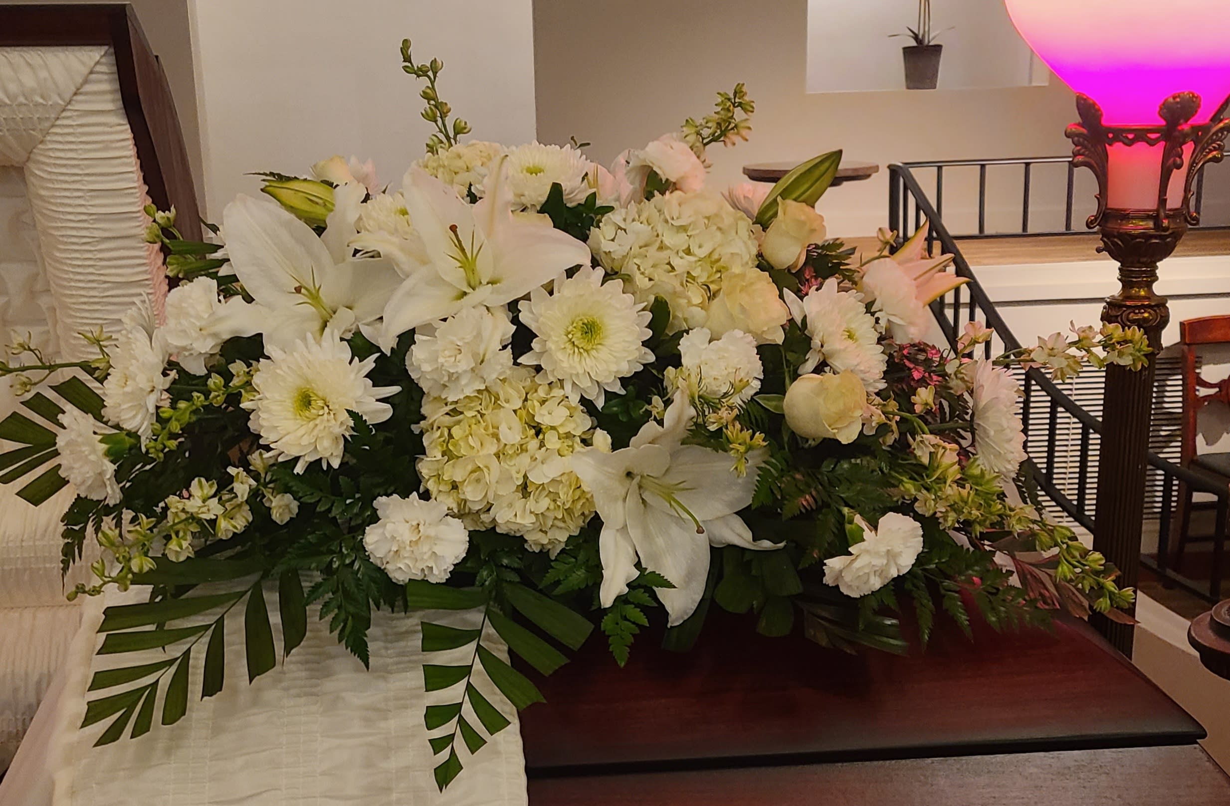 Large white floral arrangement with lilies, daisies, and hydrangeas