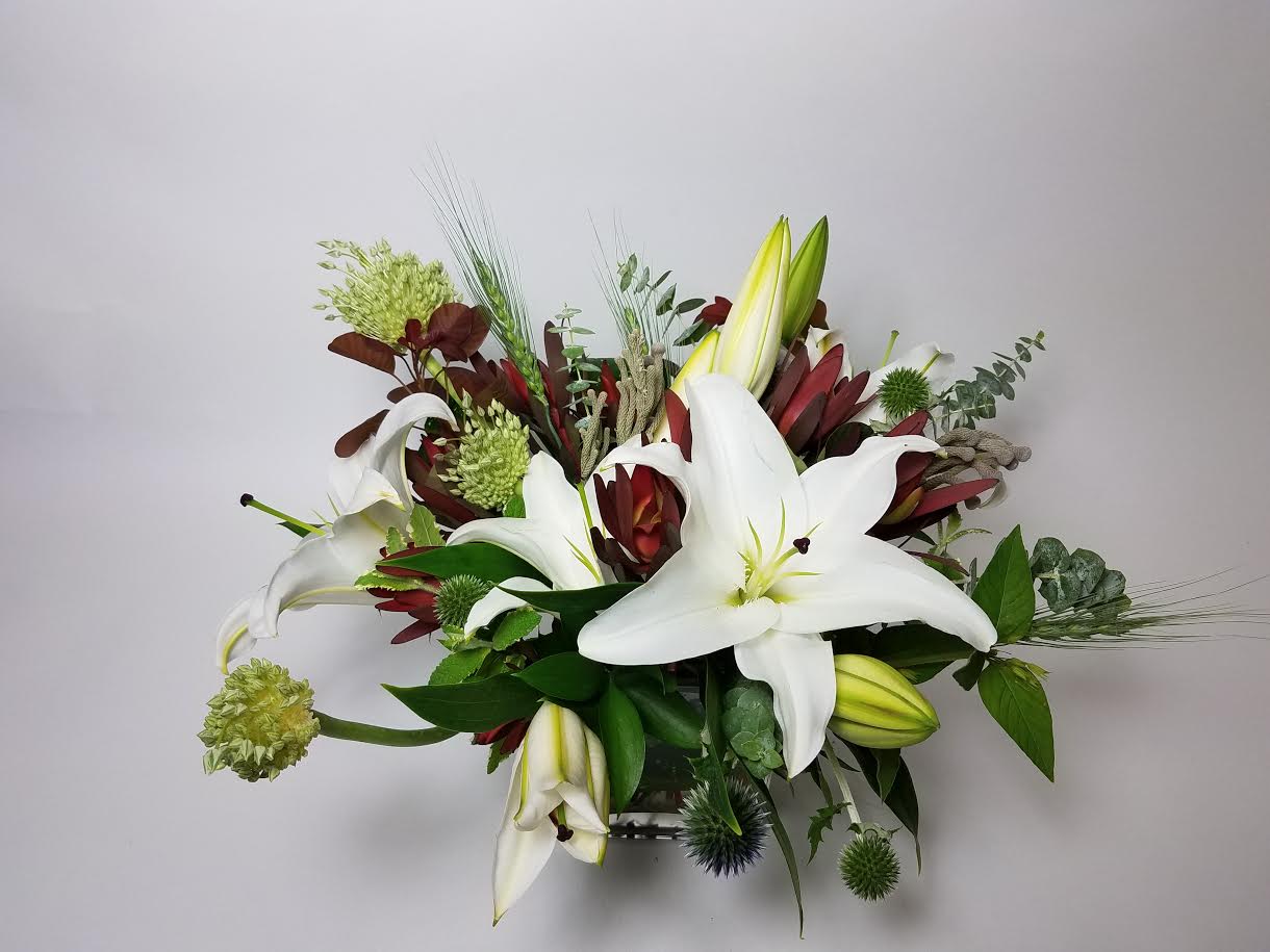 White lilies and burgundy flowers in a low arrangement