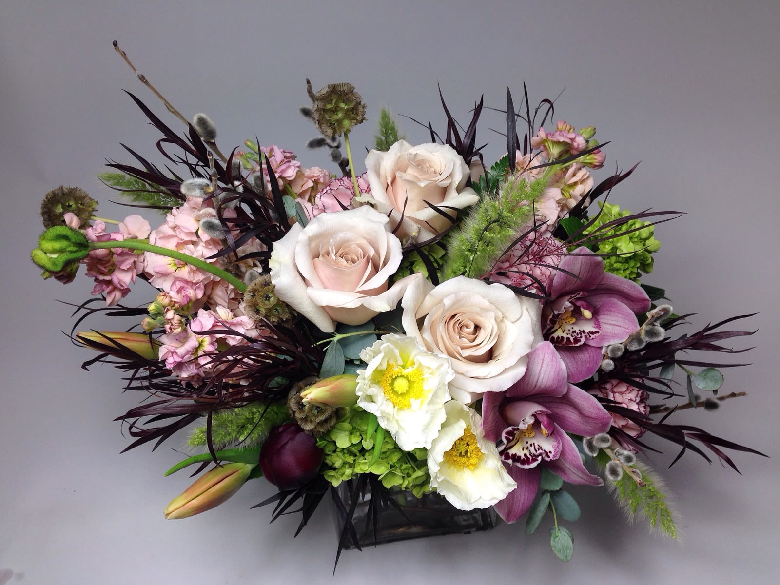 Mixed bouquet with pale roses, purple orchids, and white blooms