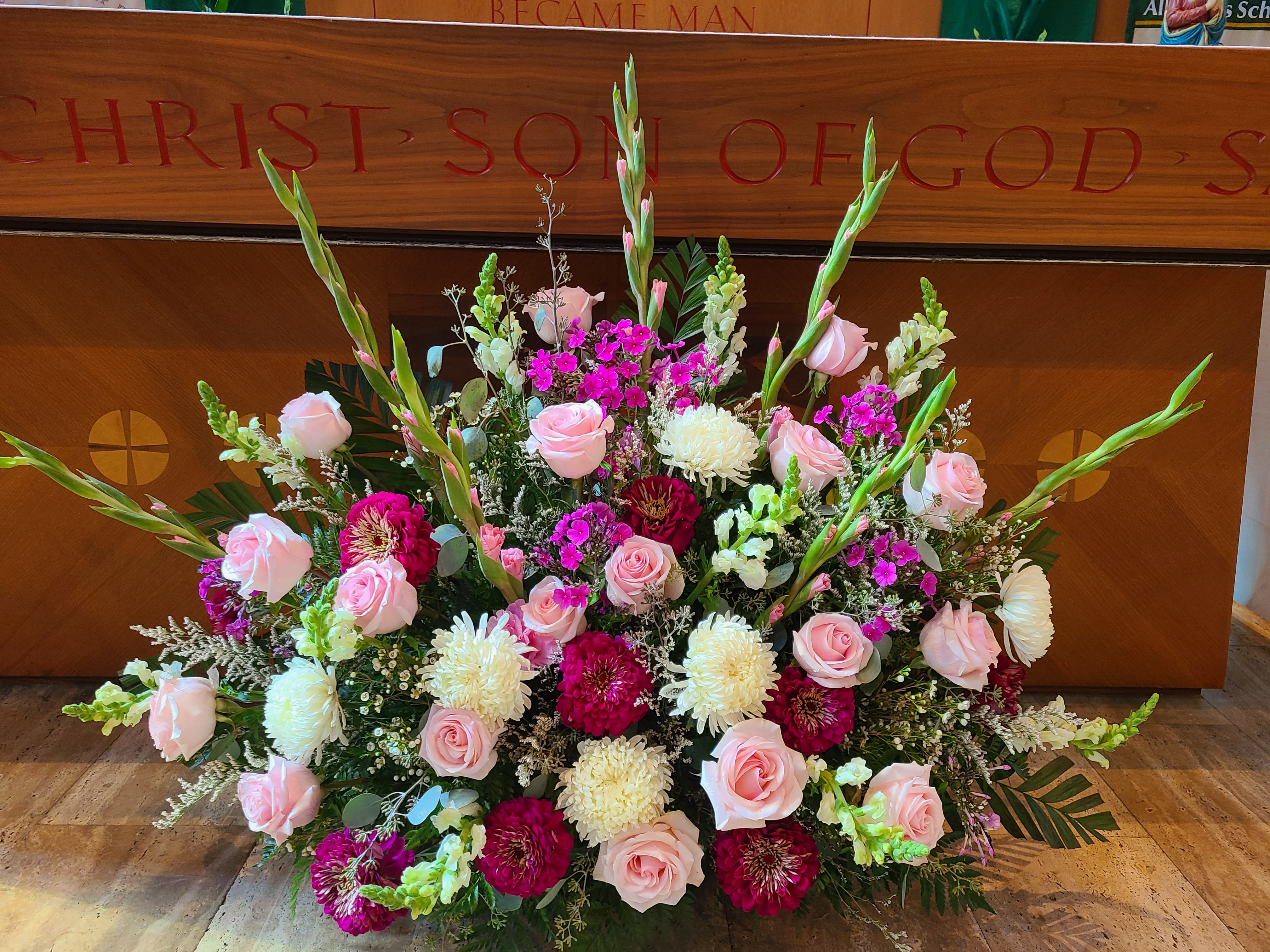 Large floral arrangement with pink roses, white mums, and magenta blooms