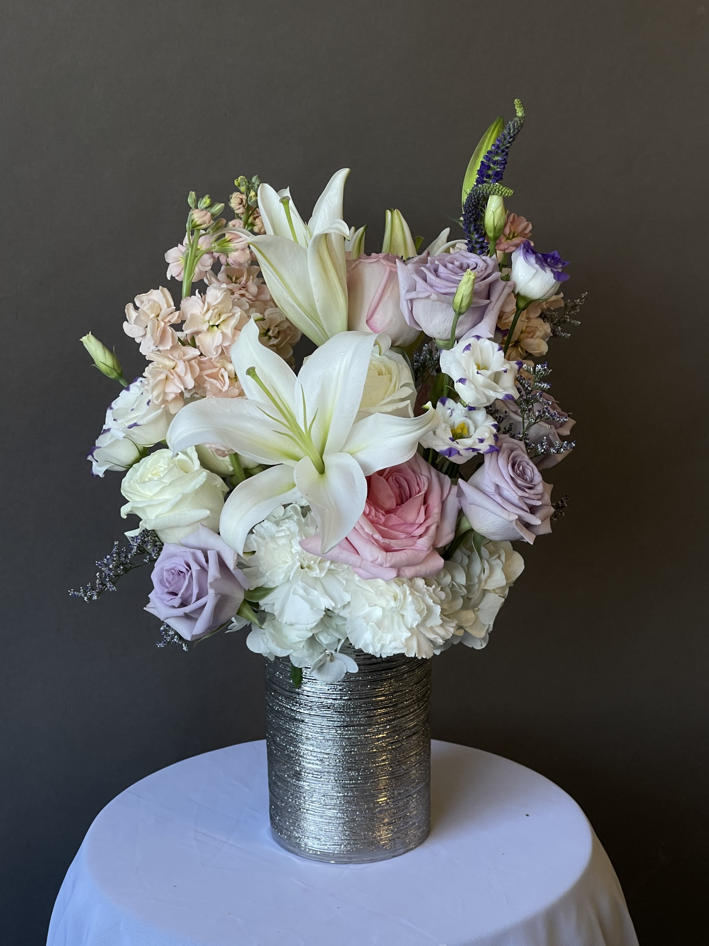 Pastel bouquet of lilies, roses, and carnations in a silver vase