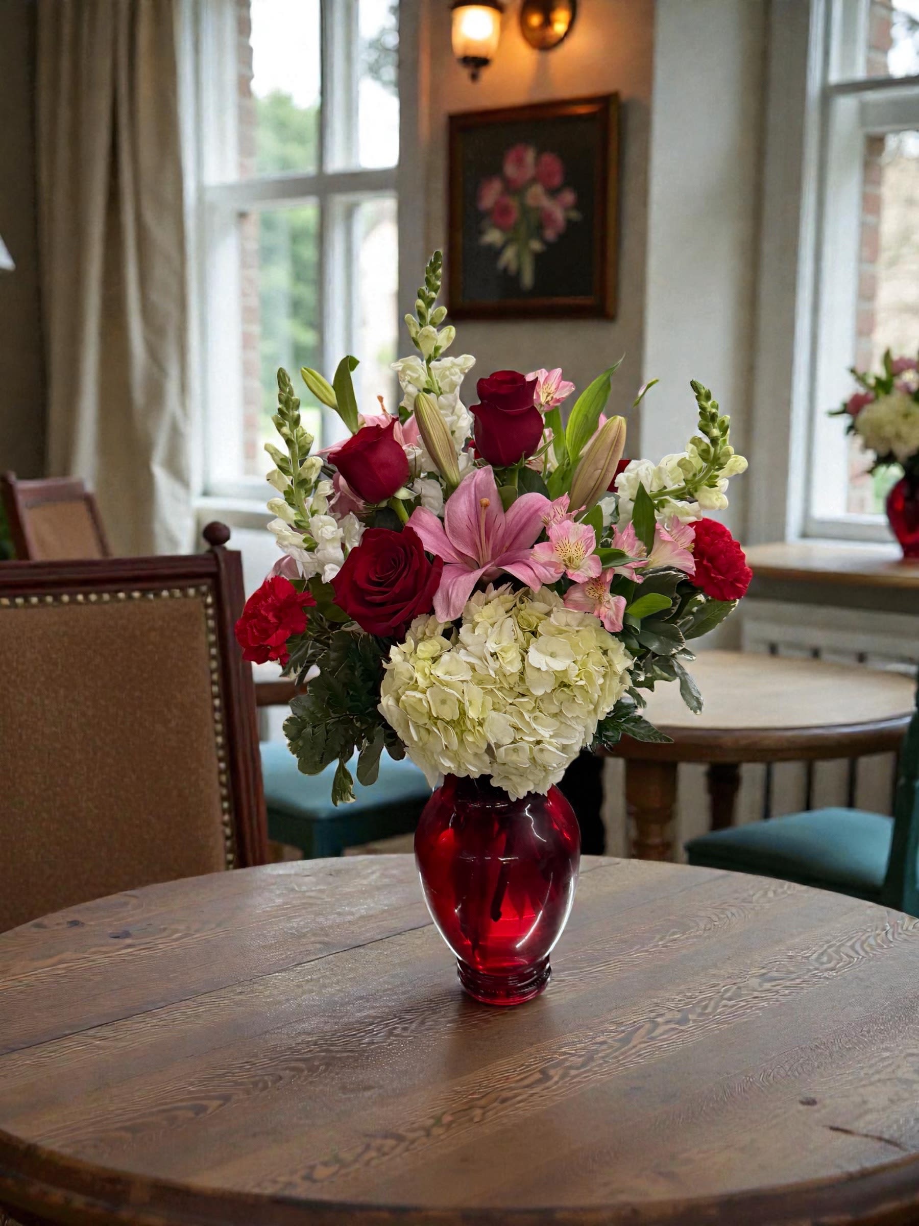Mixed pink and red flowers in a red glass vase on a table