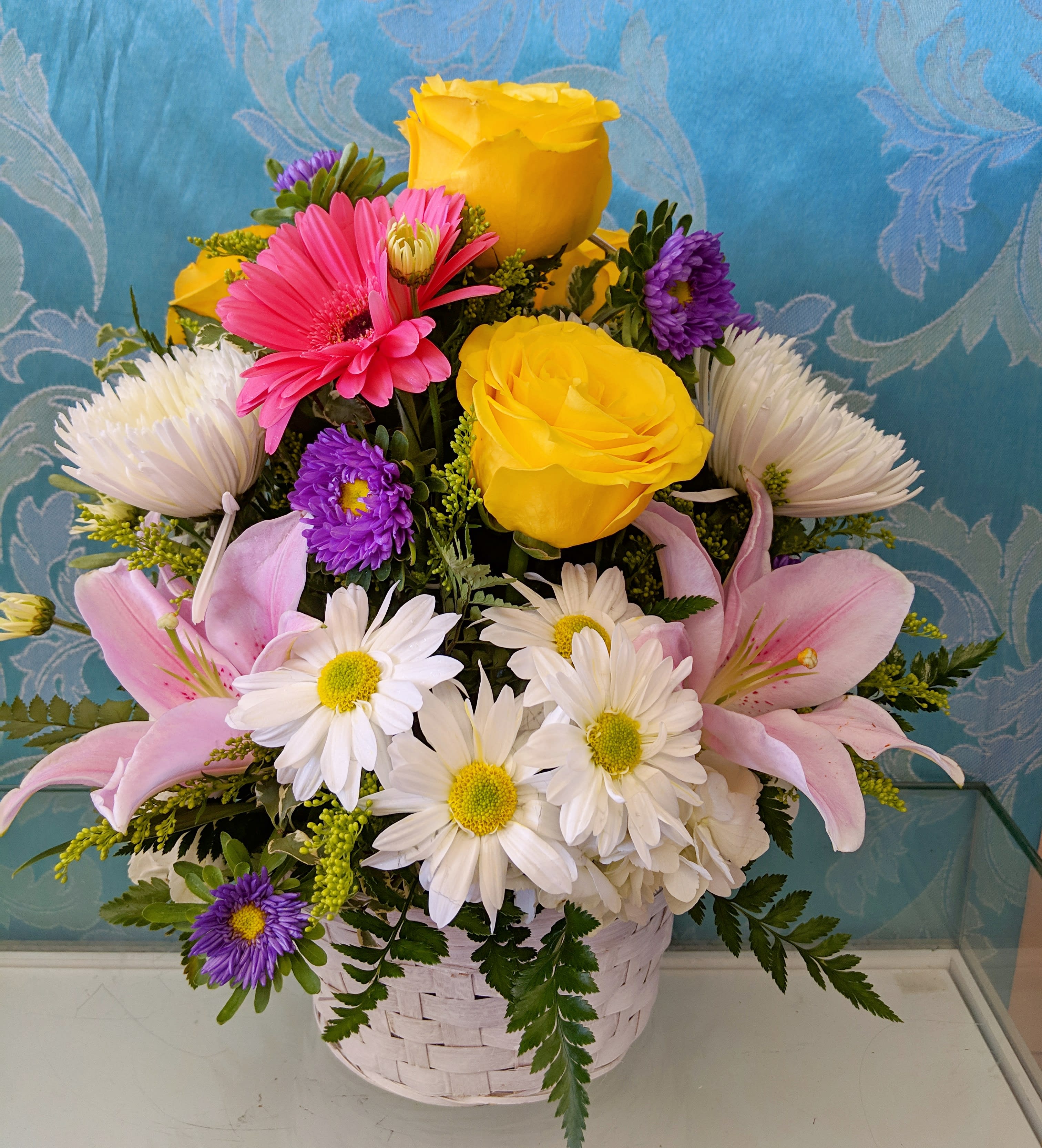 Basket arrangement with yellow roses, pink lilies, and white daisies