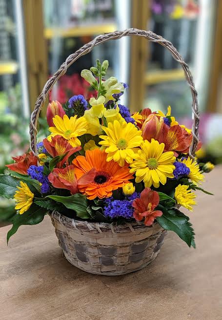 Basket of mixed yellow, orange, red, and purple flowers