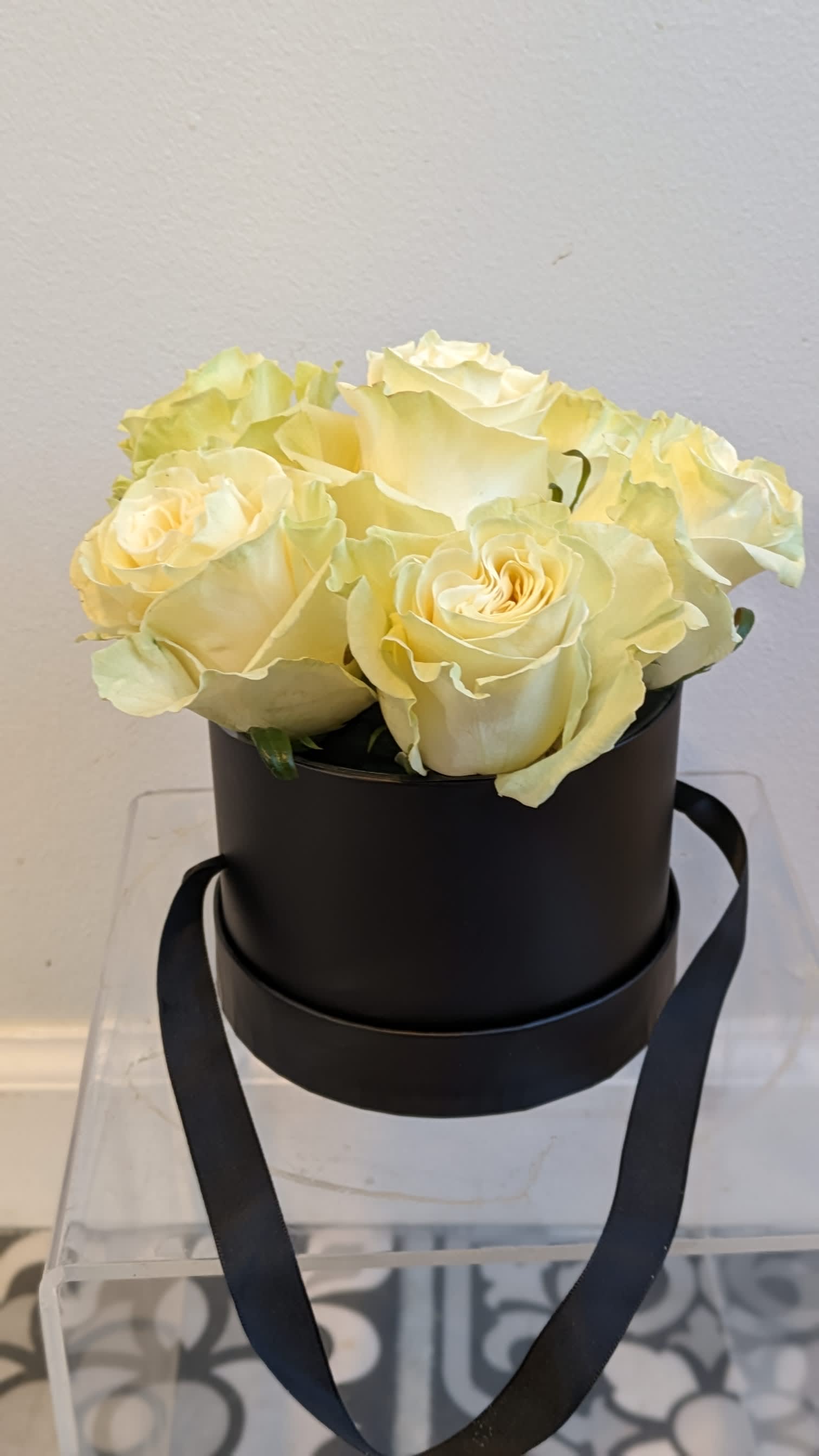 Cream roses arranged in a black round box with ribbon