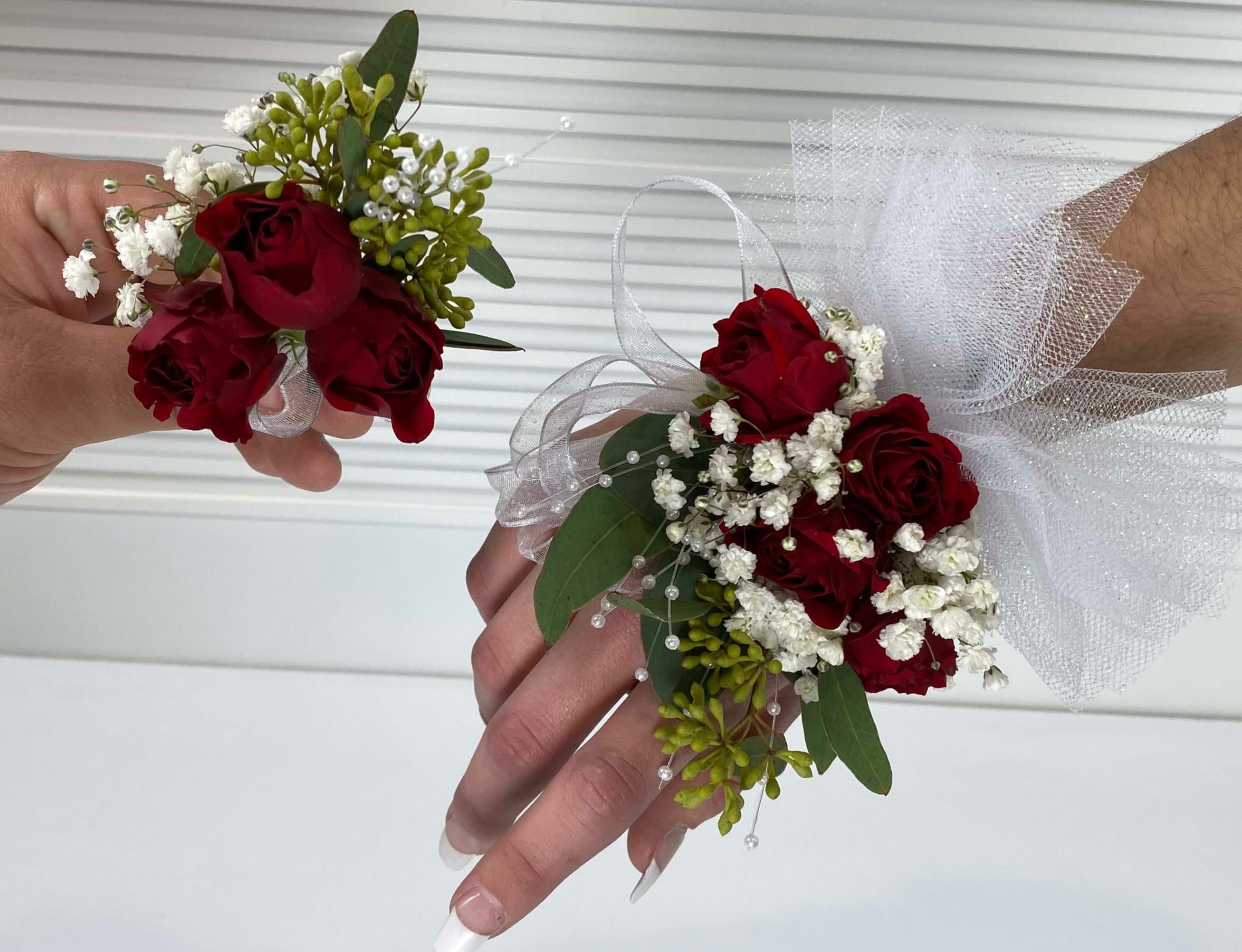 Red rose wrist corsages with white baby's breath and tulle ribbon