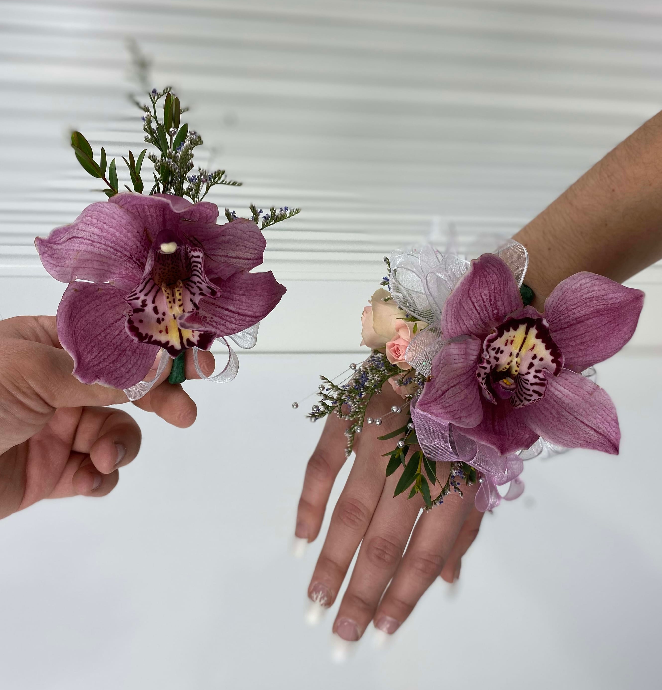 Purple orchid corsages worn on wrists with ribbon accents