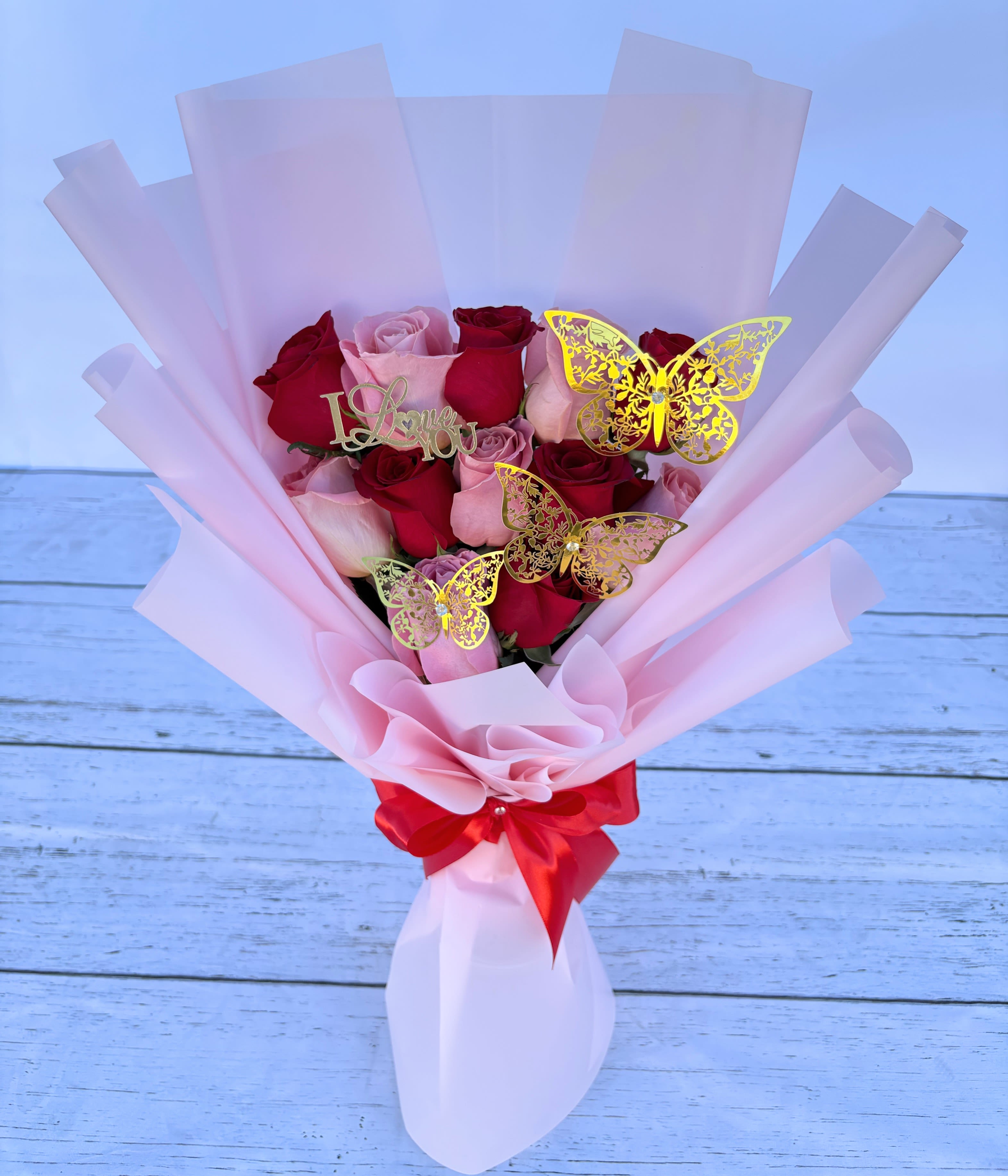Pink and red rose bouquet with butterfly picks and a red ribbon