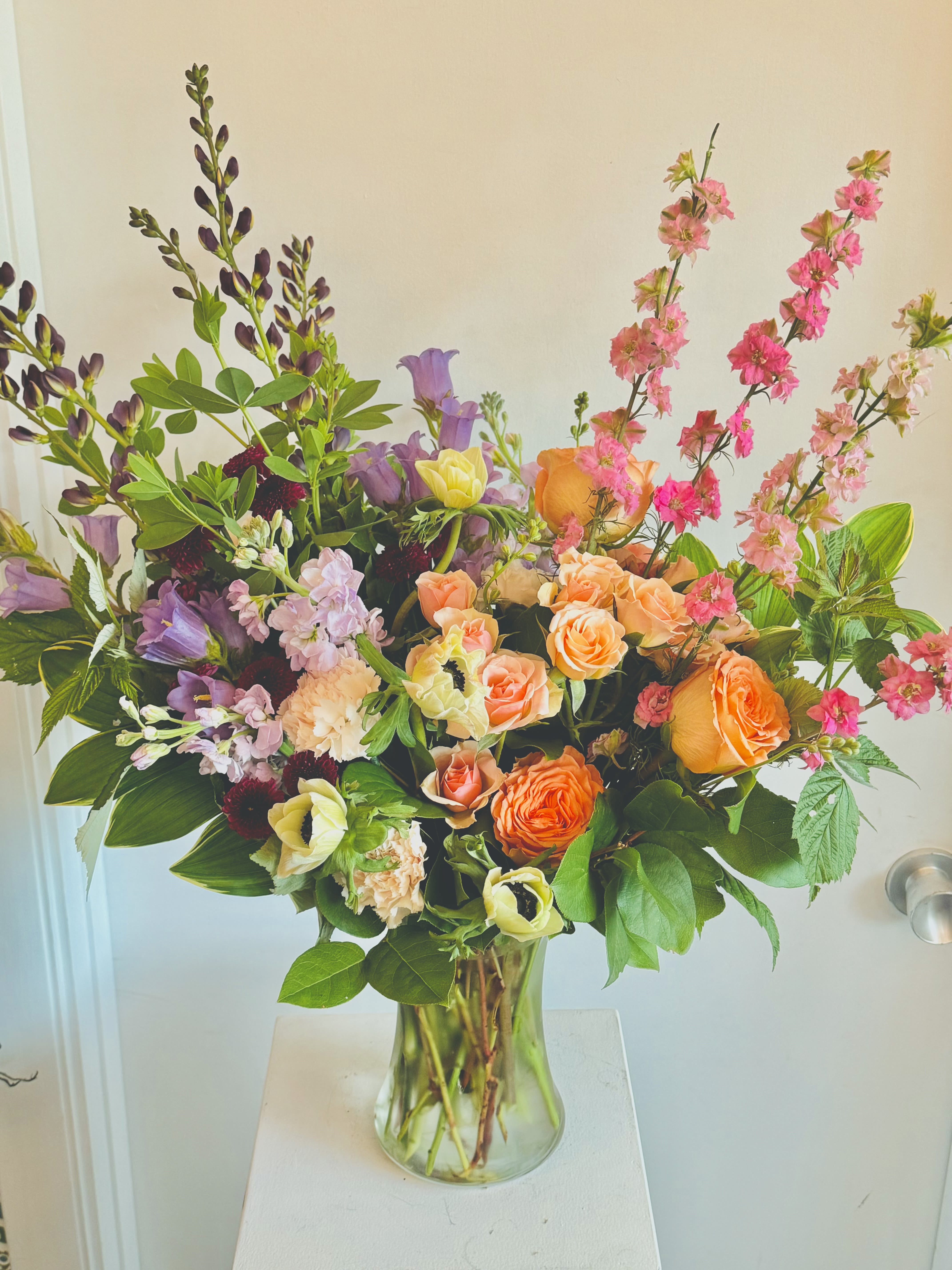 Mixed bouquet of orange, pink, and purple flowers in a clear glass vase
