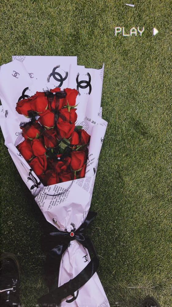 Bouquet of red roses wrapped in white paper with a black ribbon