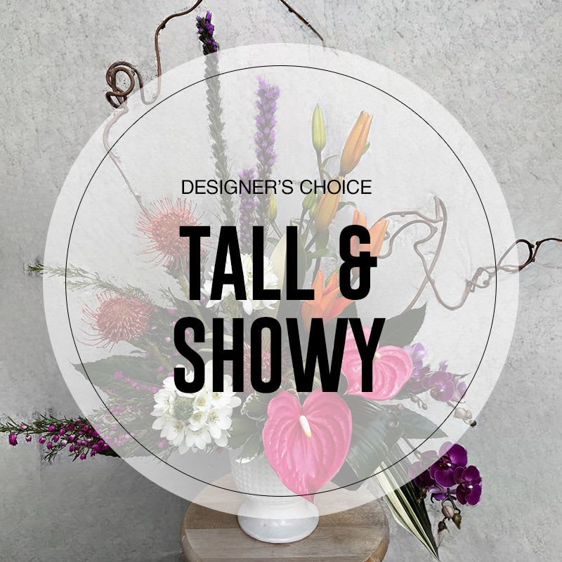 Tall floral arrangement in a white vase with pink and purple blooms