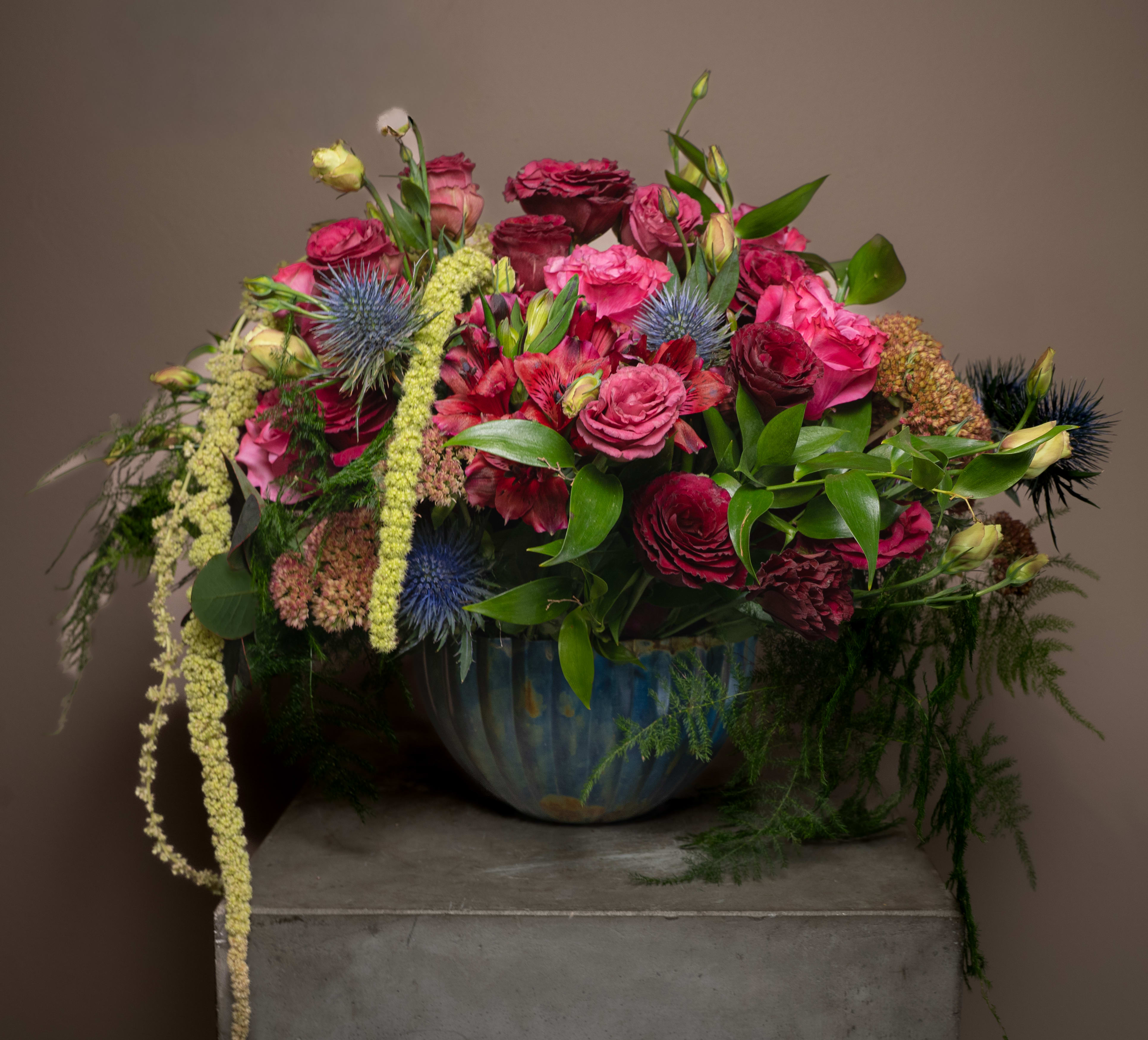 Large mixed bouquet of pink and burgundy flowers in a blue vase
