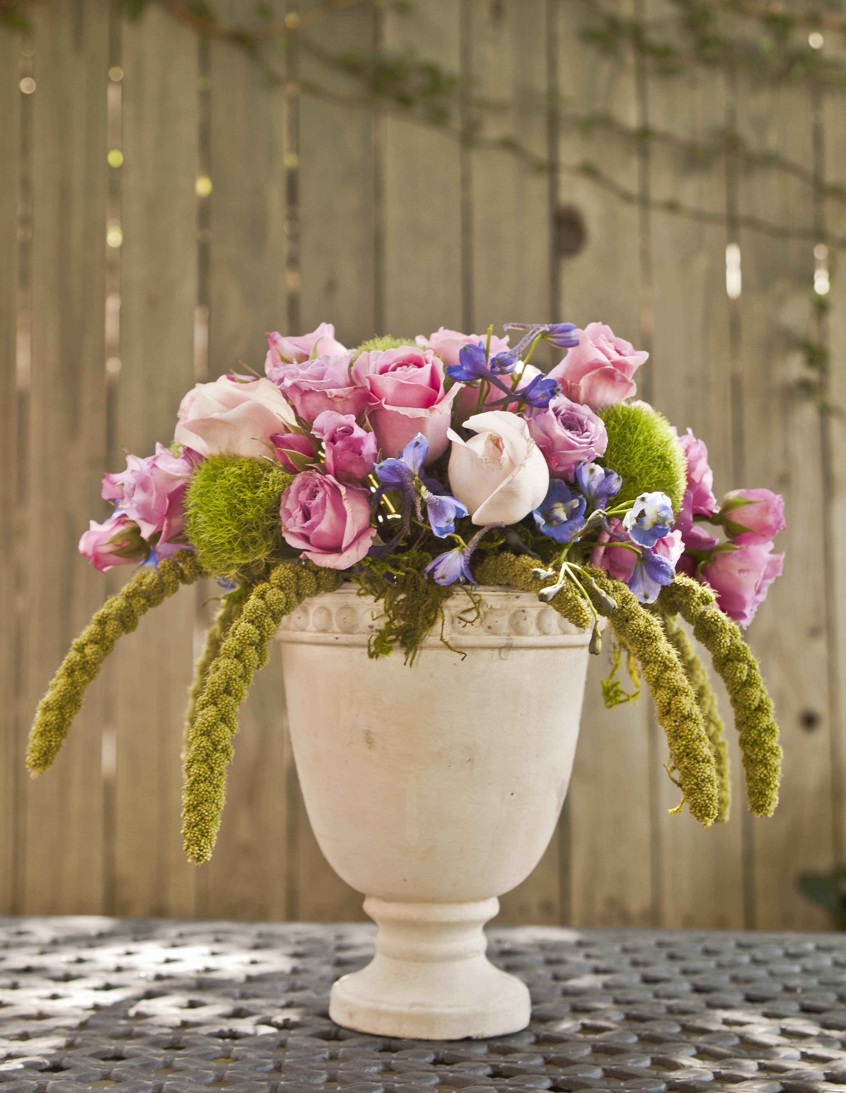 Pink and lavender roses arranged in a white pedestal vase
