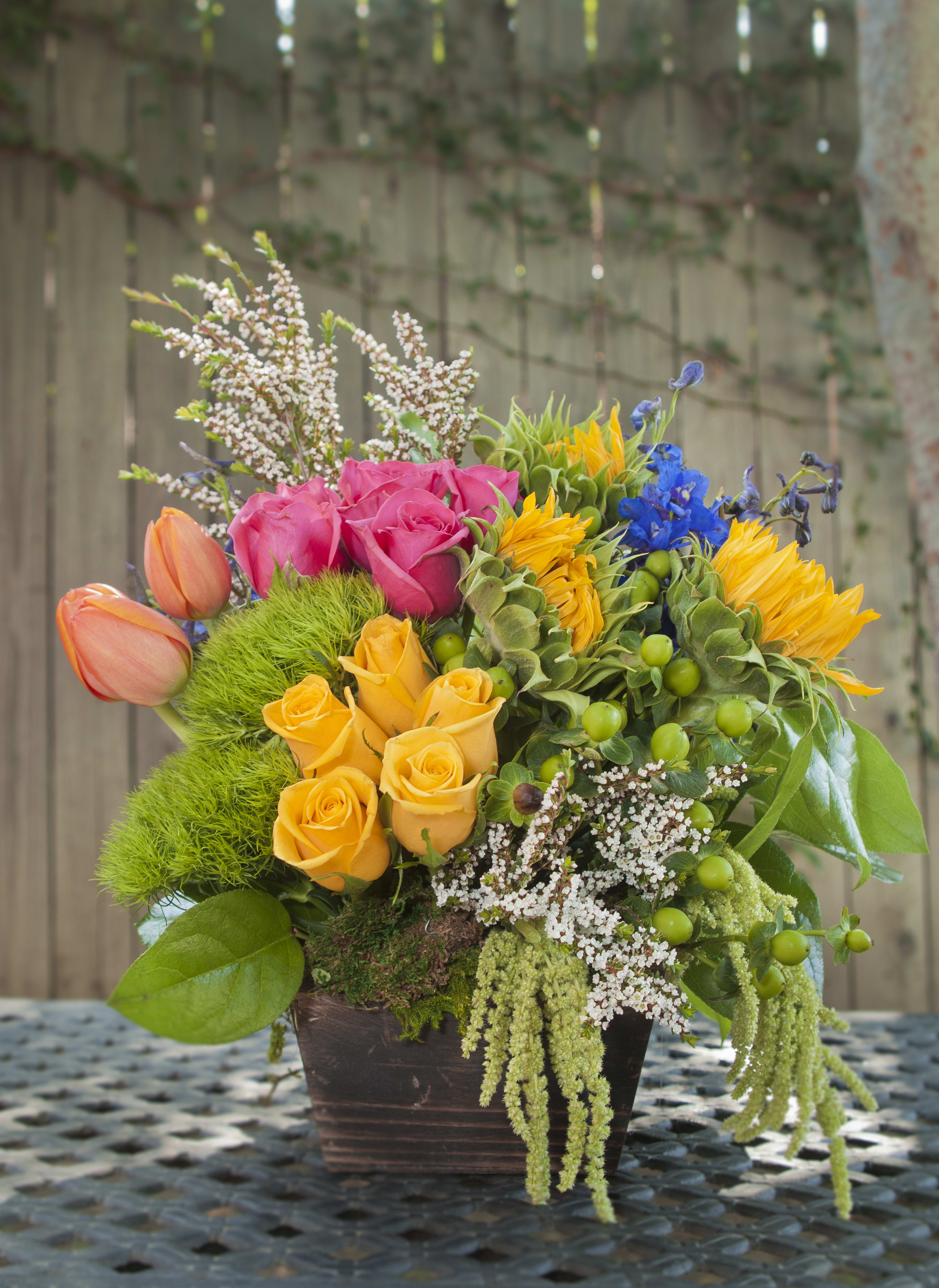 Delizia Pomeriggio  - Experience the perfect mix of roses, sunflowers, and more with our vibrant floral arrangement presented in a lovely wooden box. Each arrangement is crafted to capture the style depicted in the picture, though variations may occur due to weather and flower conditions. Rest assured, our team strives to match your arrangement as closely as possible to the pictured item. Ideal for adding a burst of color and natural beauty to any space or occasion. Order now to bring this delightful arrangement into your home or send it as a thoughtful gift!