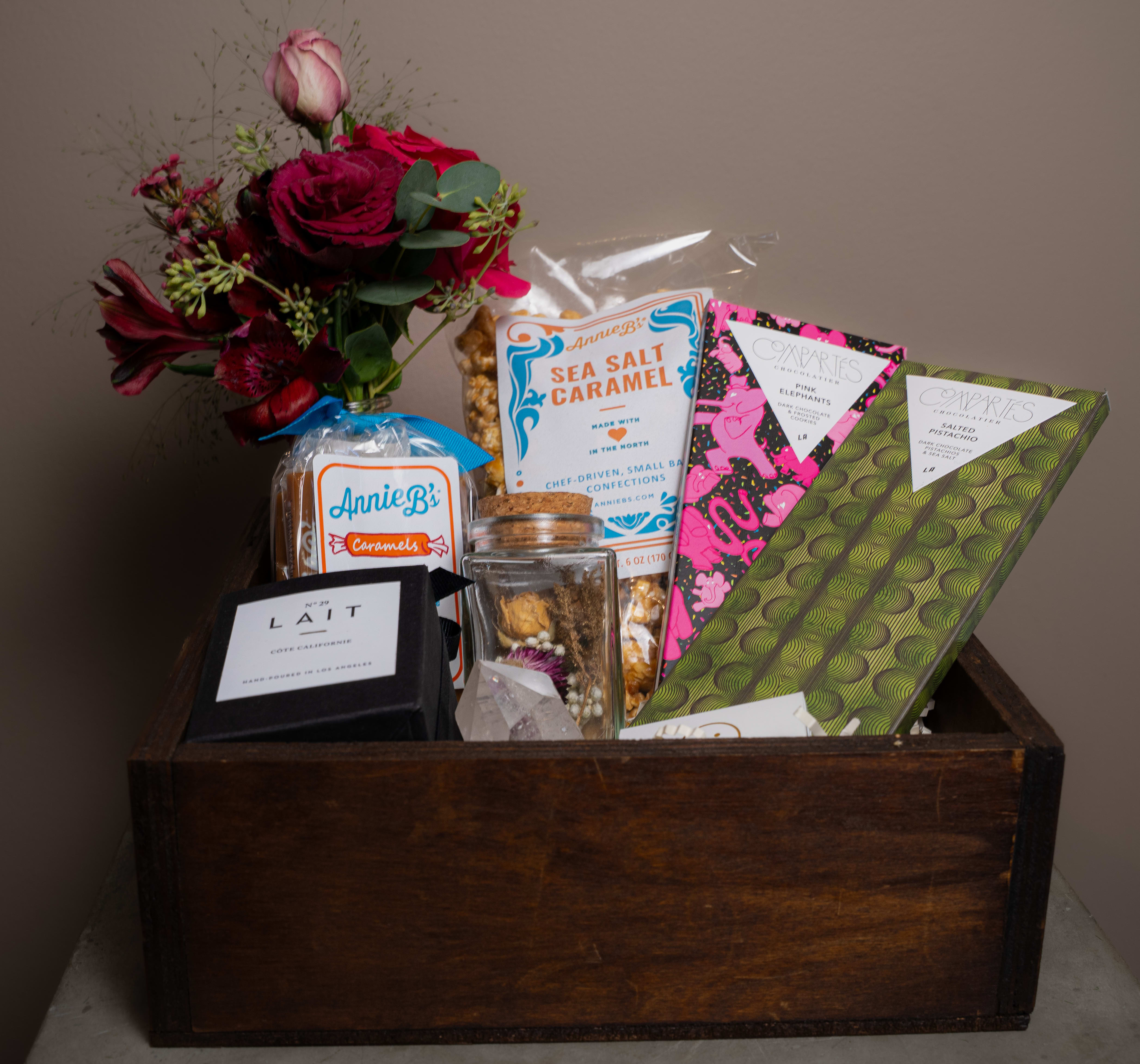 Gift basket with a burgundy flower bouquet and assorted sweets