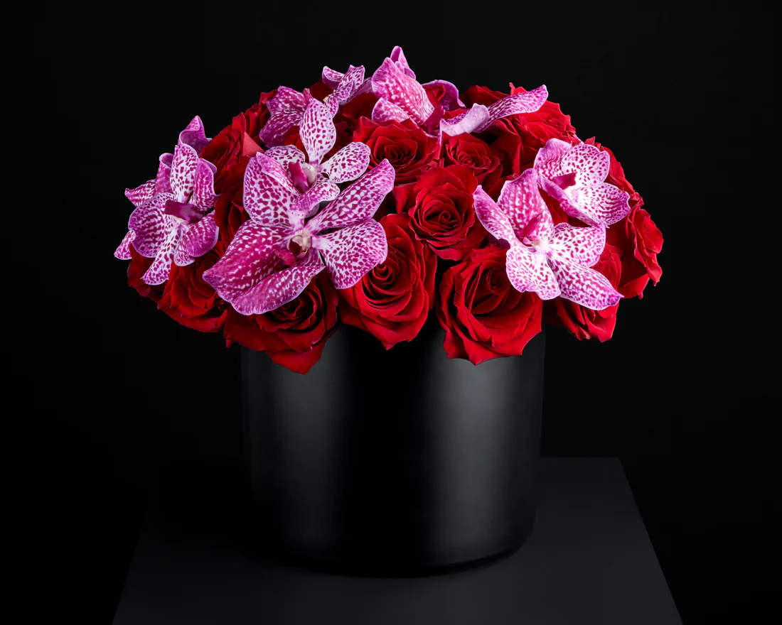 Dolce Rosa - Indulge in the exquisite blend of 24 premium red roses and luscious orchids, meticulously arranged in a sleek black vase. This floral masterpiece captures the essence of passion and elegance, creating a visual symphony that's as tempting as a decadent treat for the senses. Perfect for expressing love, admiration, or celebrating a special occasion with sophistication. Order now to add a touch of luxury and beauty to your surroundings!