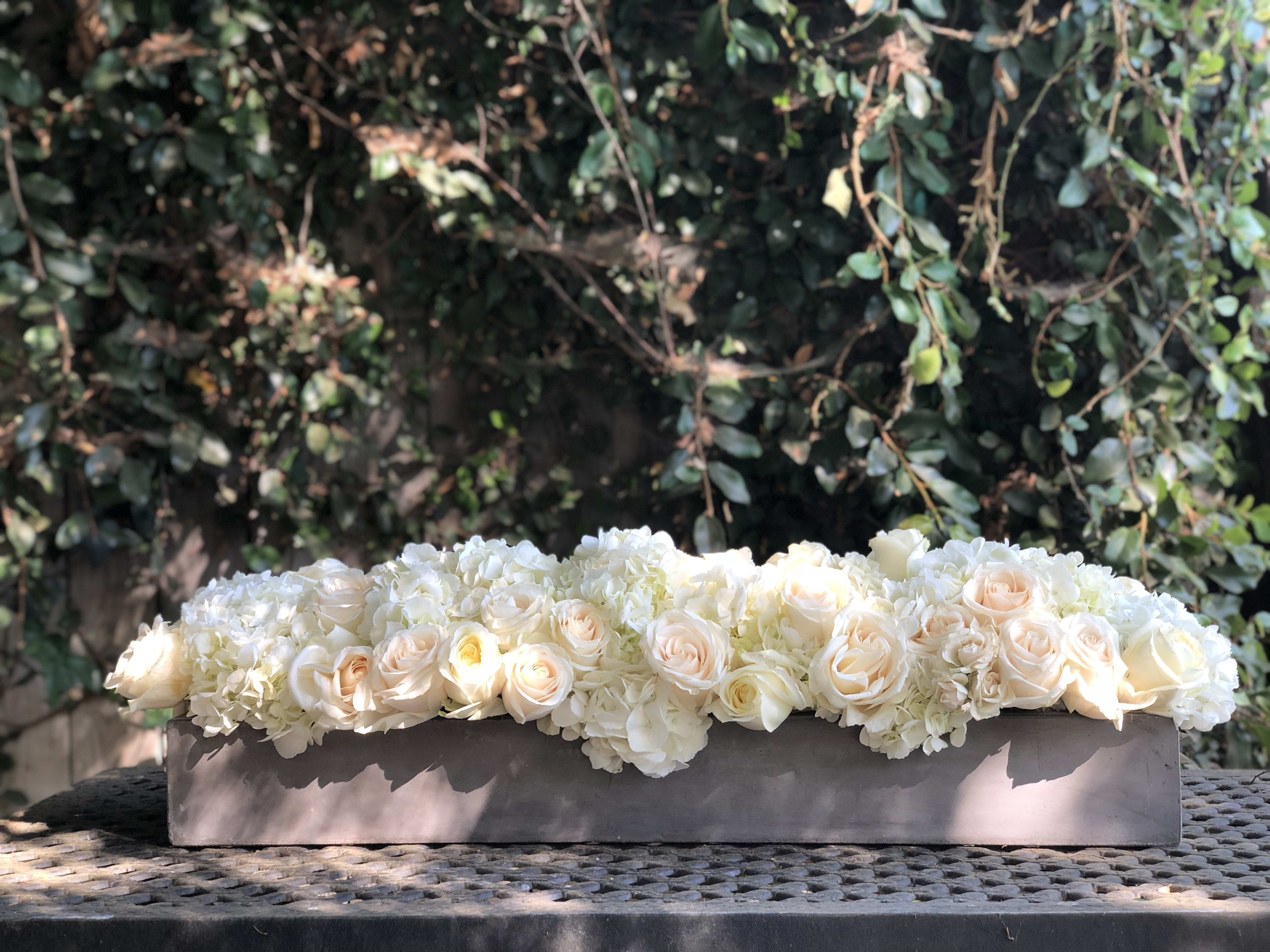 Low floral arrangement of white and blush roses in a rectangular container
