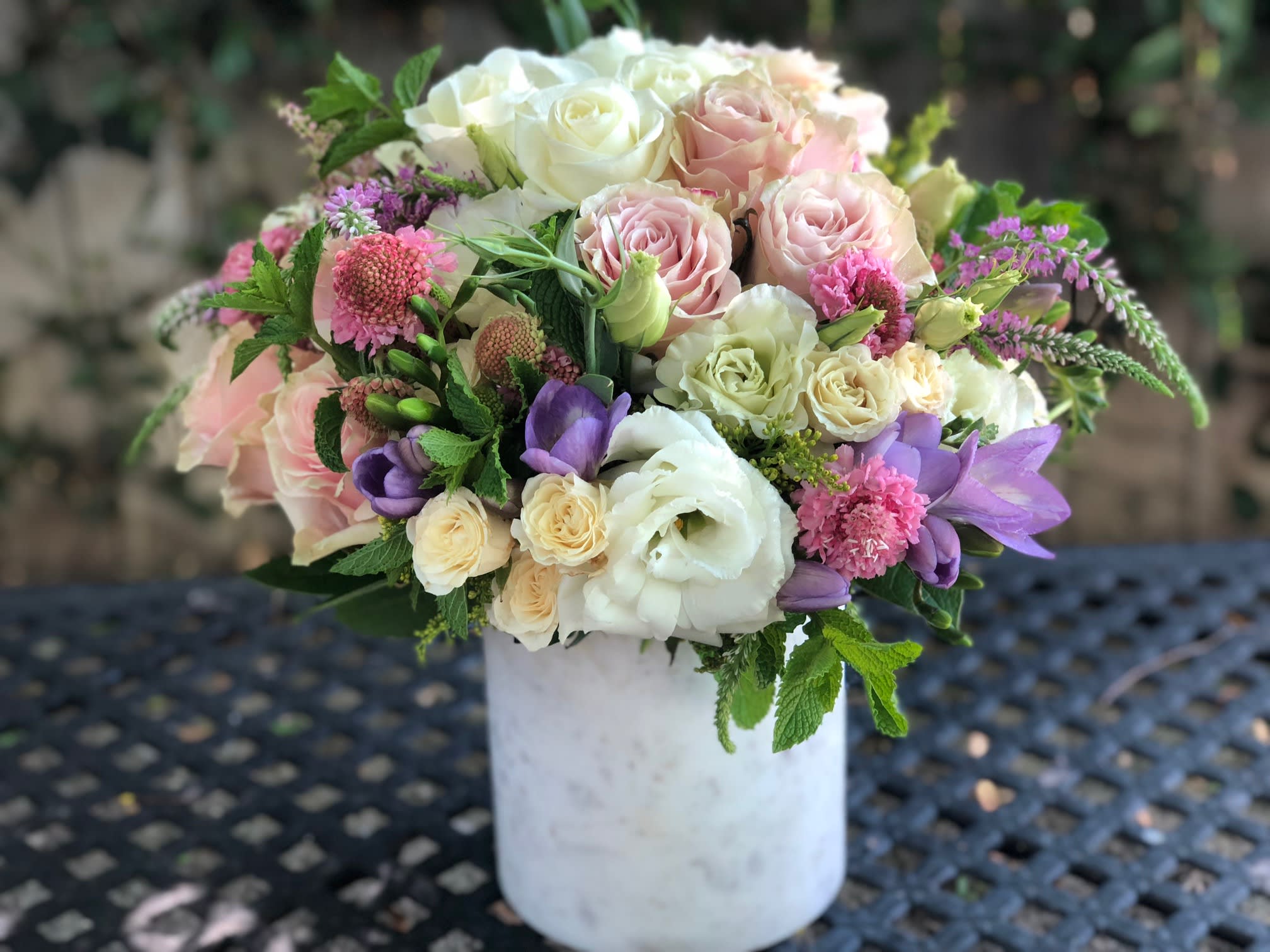 Bouquet of pink, white, and purple flowers in a white vase