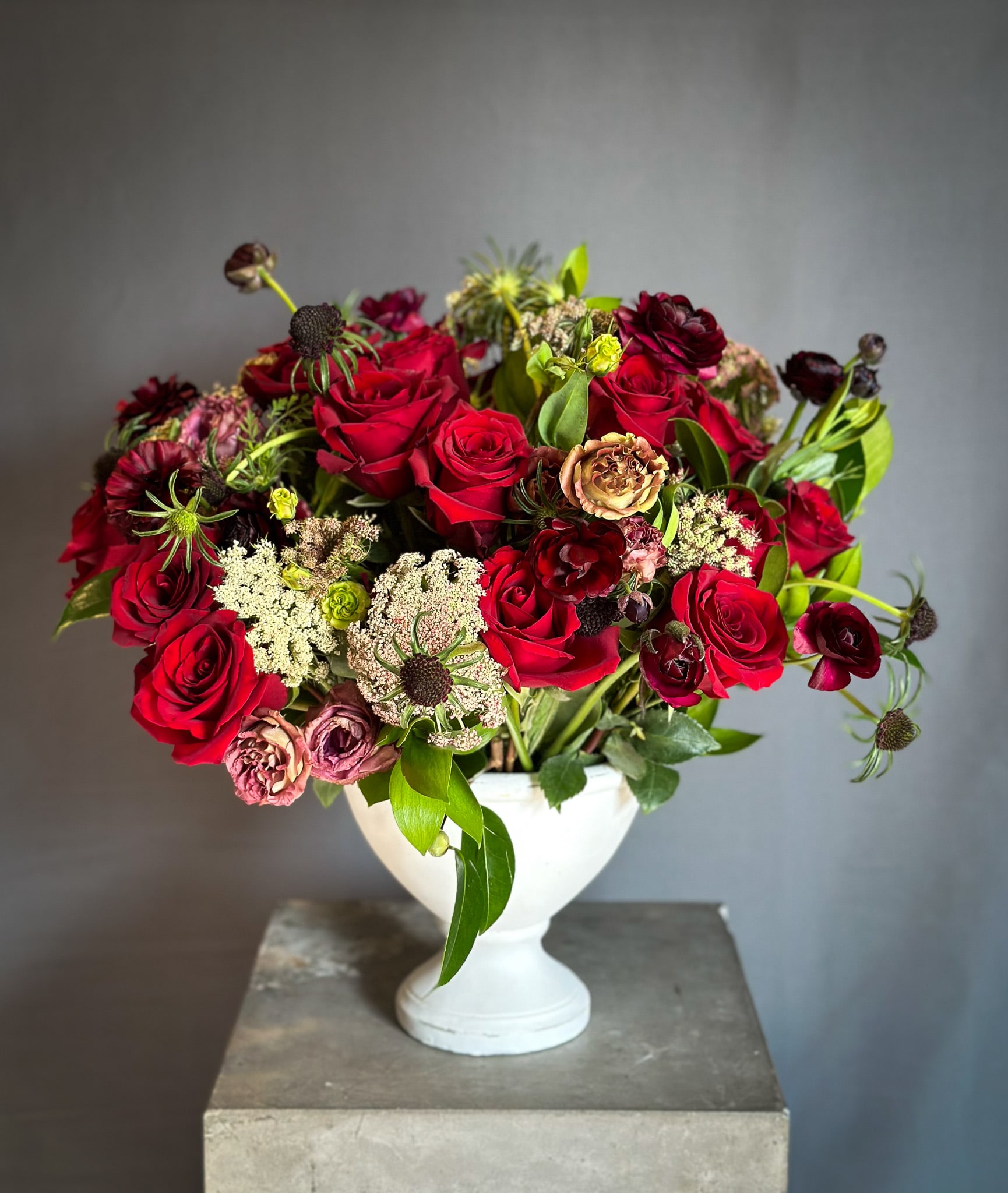 Red rose bouquet in a white pedestal vase