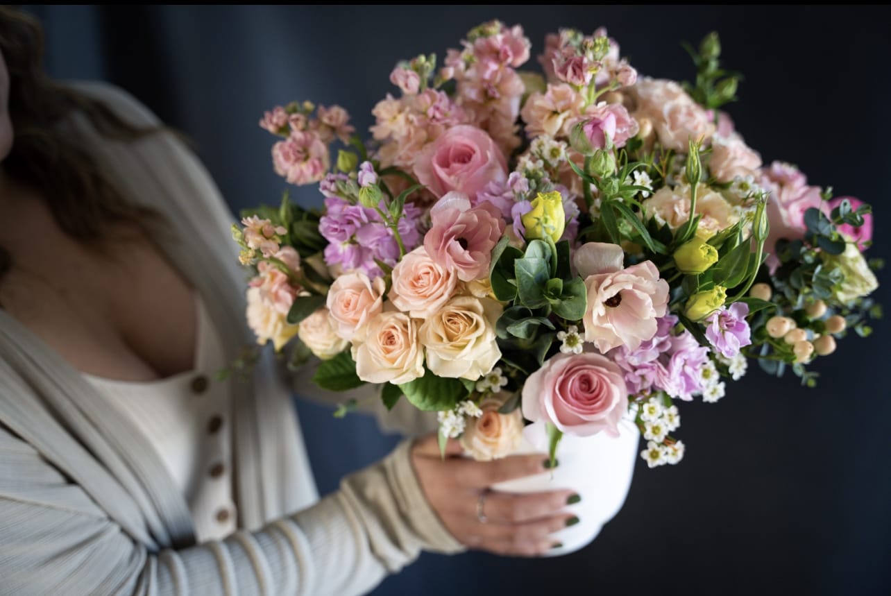 Woman holding a pastel bouquet in a white vase
