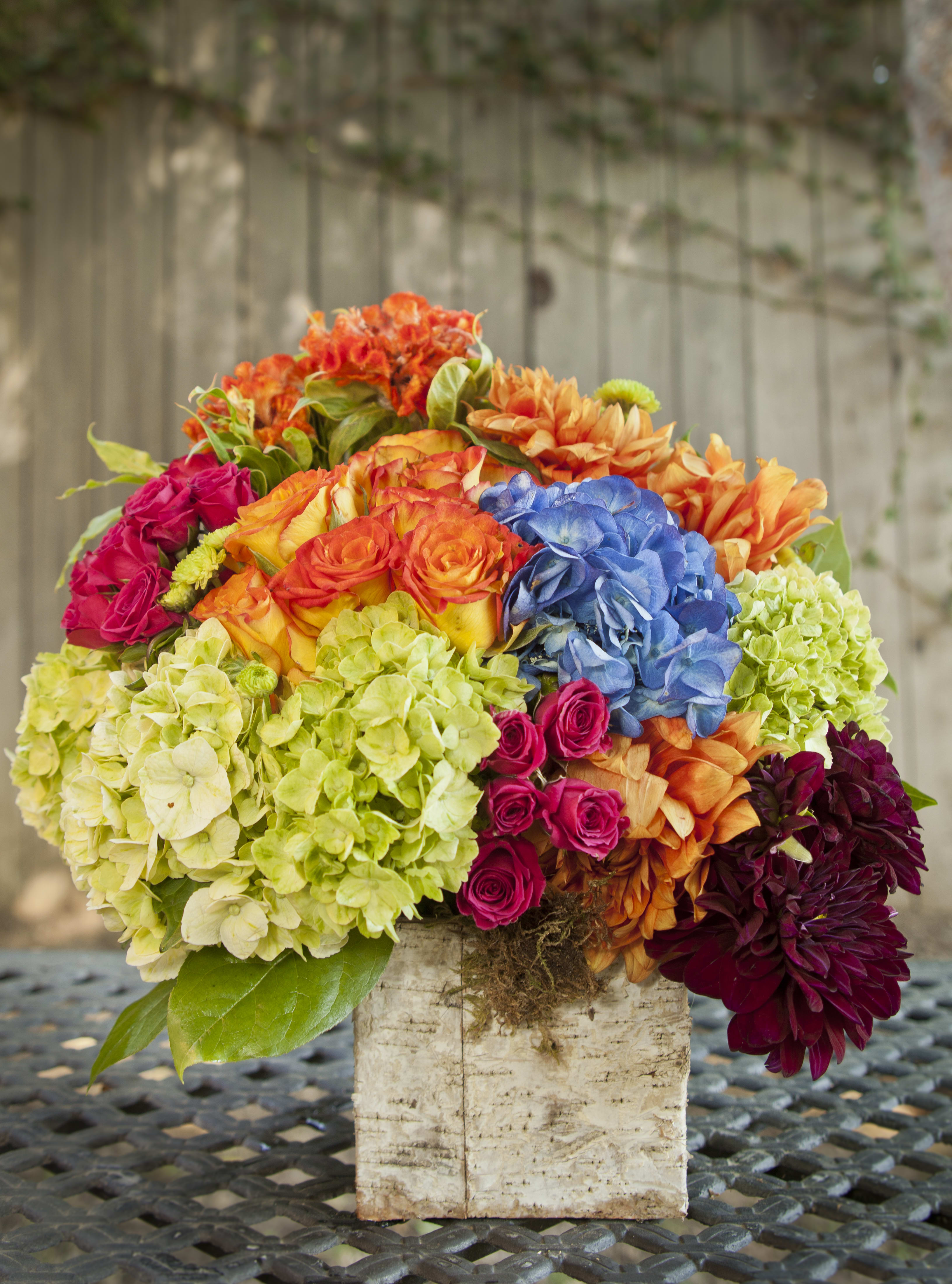 Colorful bouquet of hydrangeas, roses, and dahlias in a rustic container